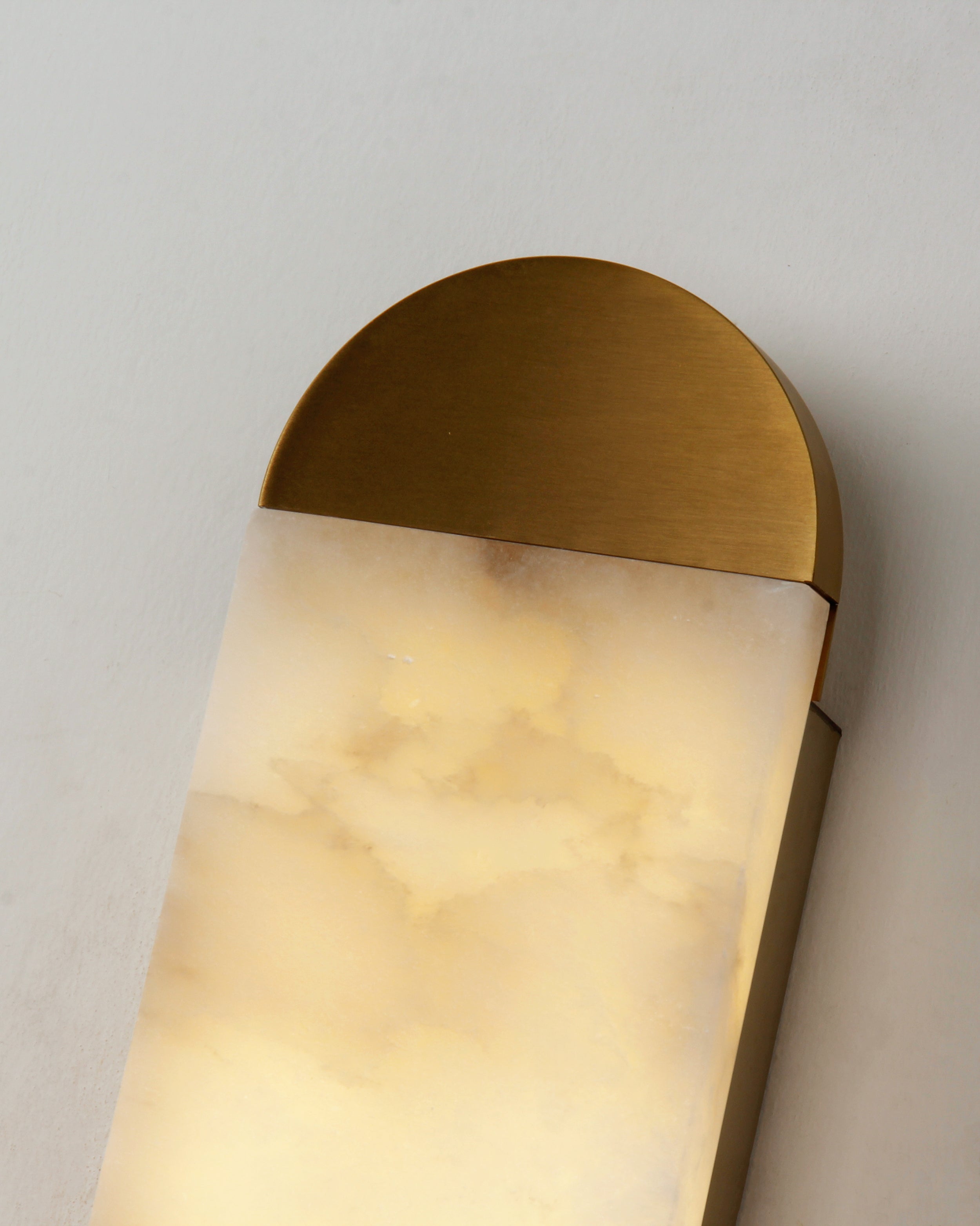 Detail of curved marble top and smooth illumination in luxury wall light design