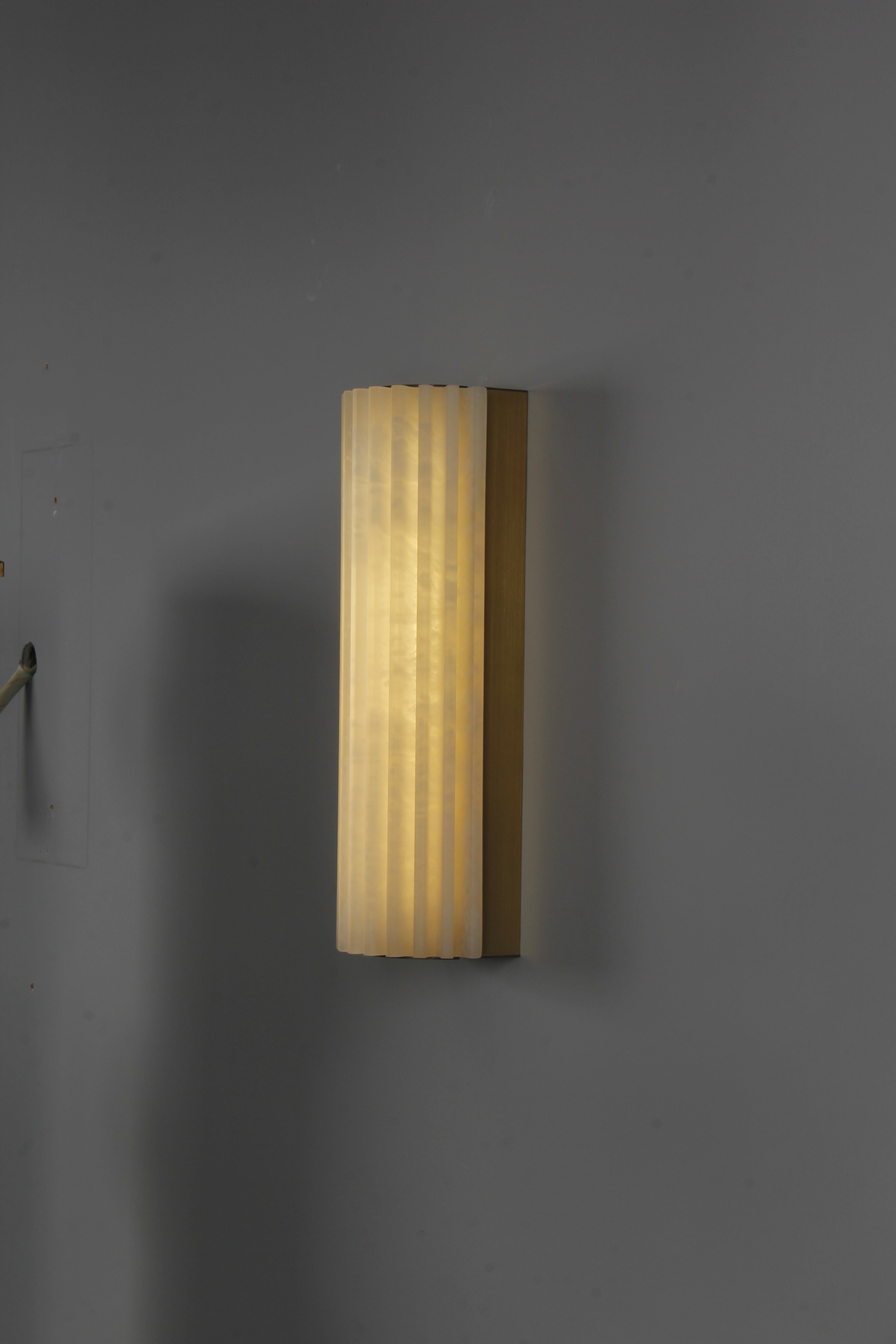 Modern interior featuring slim fluted marble wall light with warm ambient illumination