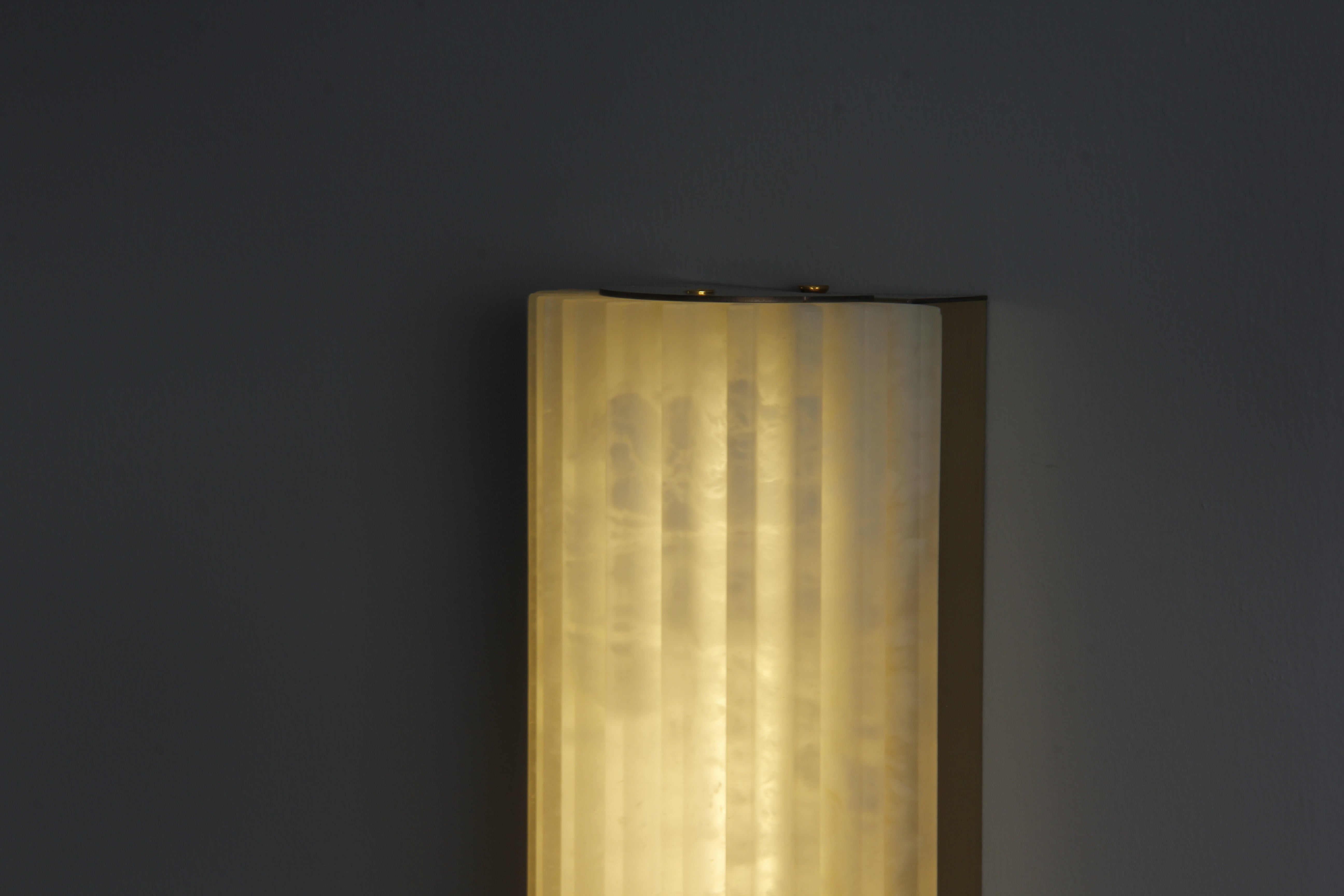 Detail of warm diffused light through fluted marble wall fixture