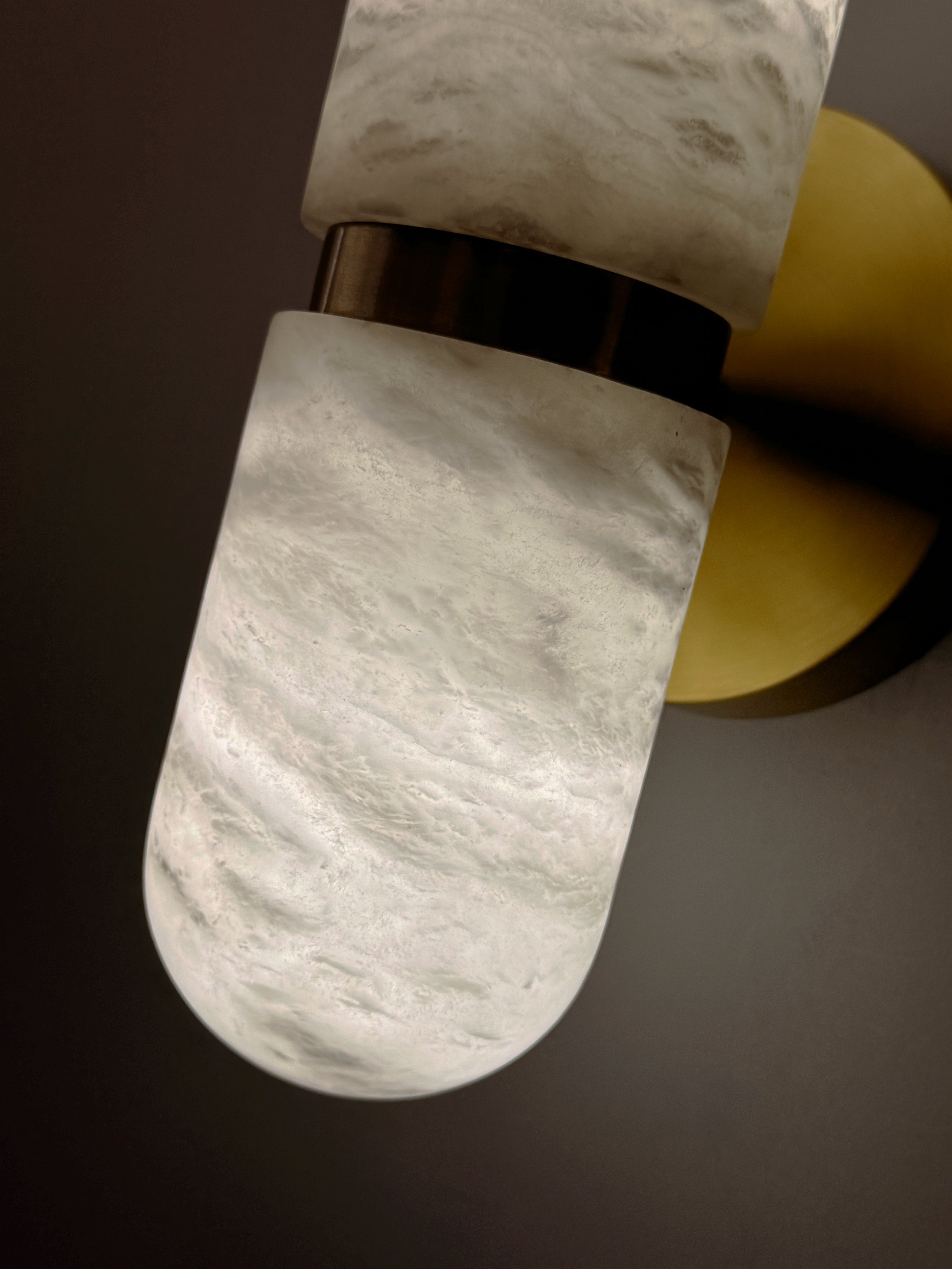 Curved sculpted marble edge detail of the Luma wall light with warm brass fitting