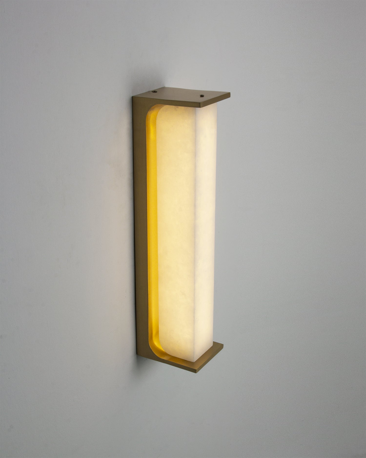 Installed VORELLI Matera marble wall light casting a soft ambient glow across a luxury interior wall with elegant curved marble form