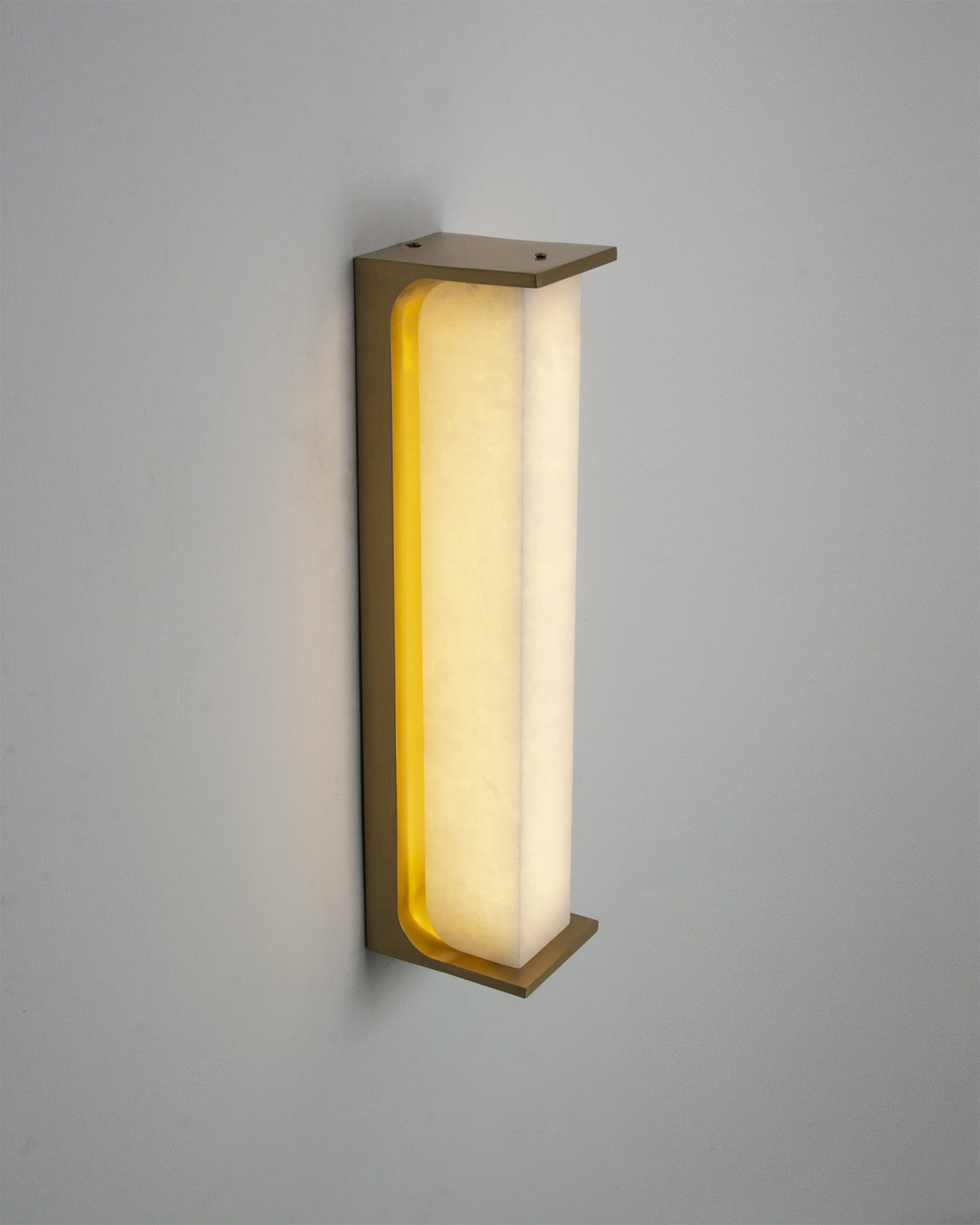 Installed VORELLI Matera marble wall light casting a soft ambient glow across a luxury interior wall with elegant curved marble form