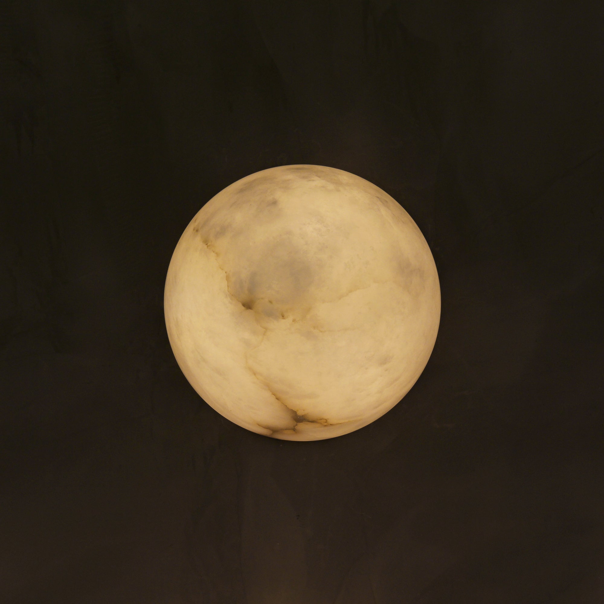 Illuminated Arona marble wall light showing natural stone texture