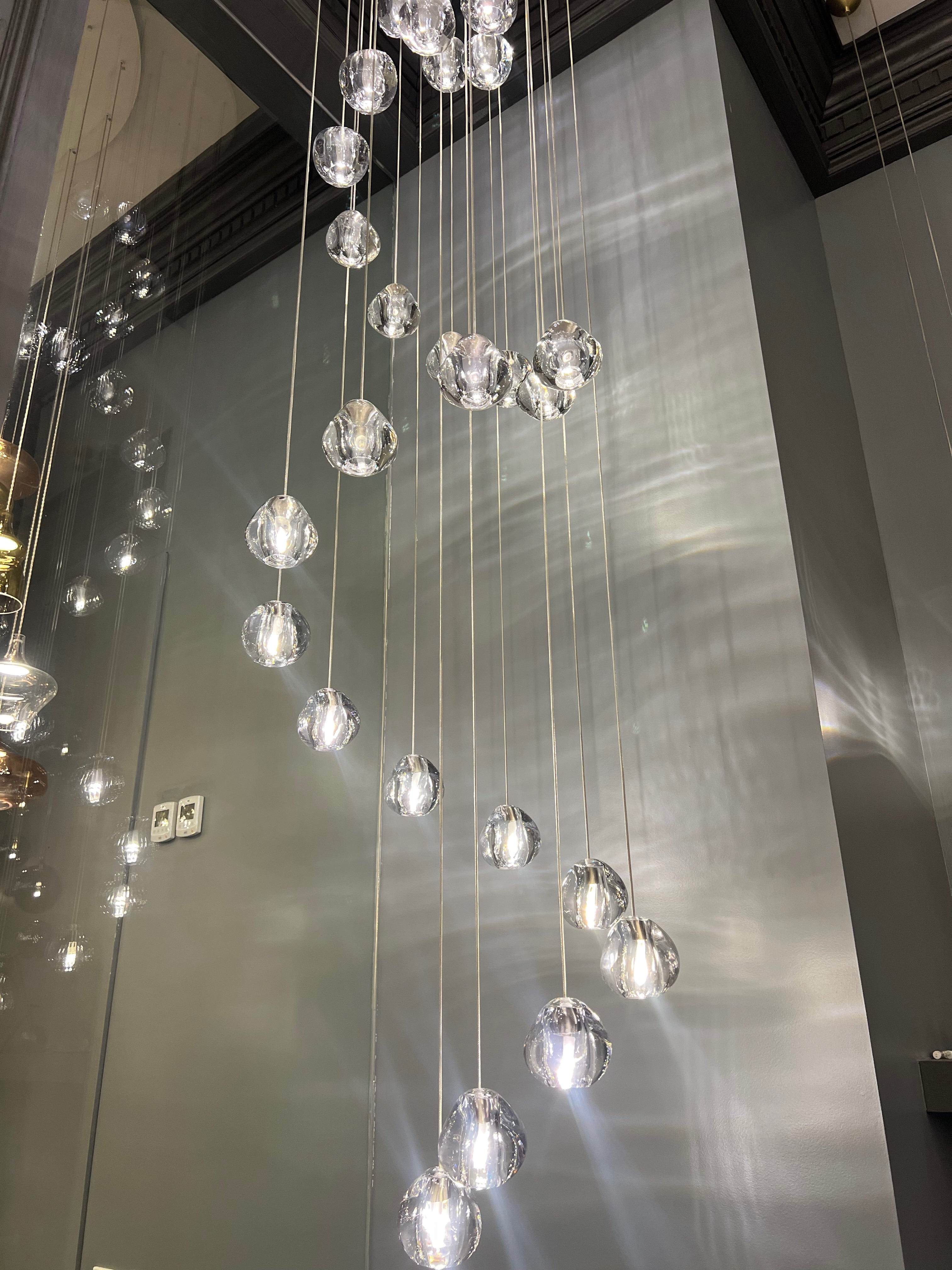 Biella glass pendant chandelier suspended in double-height stairwell
