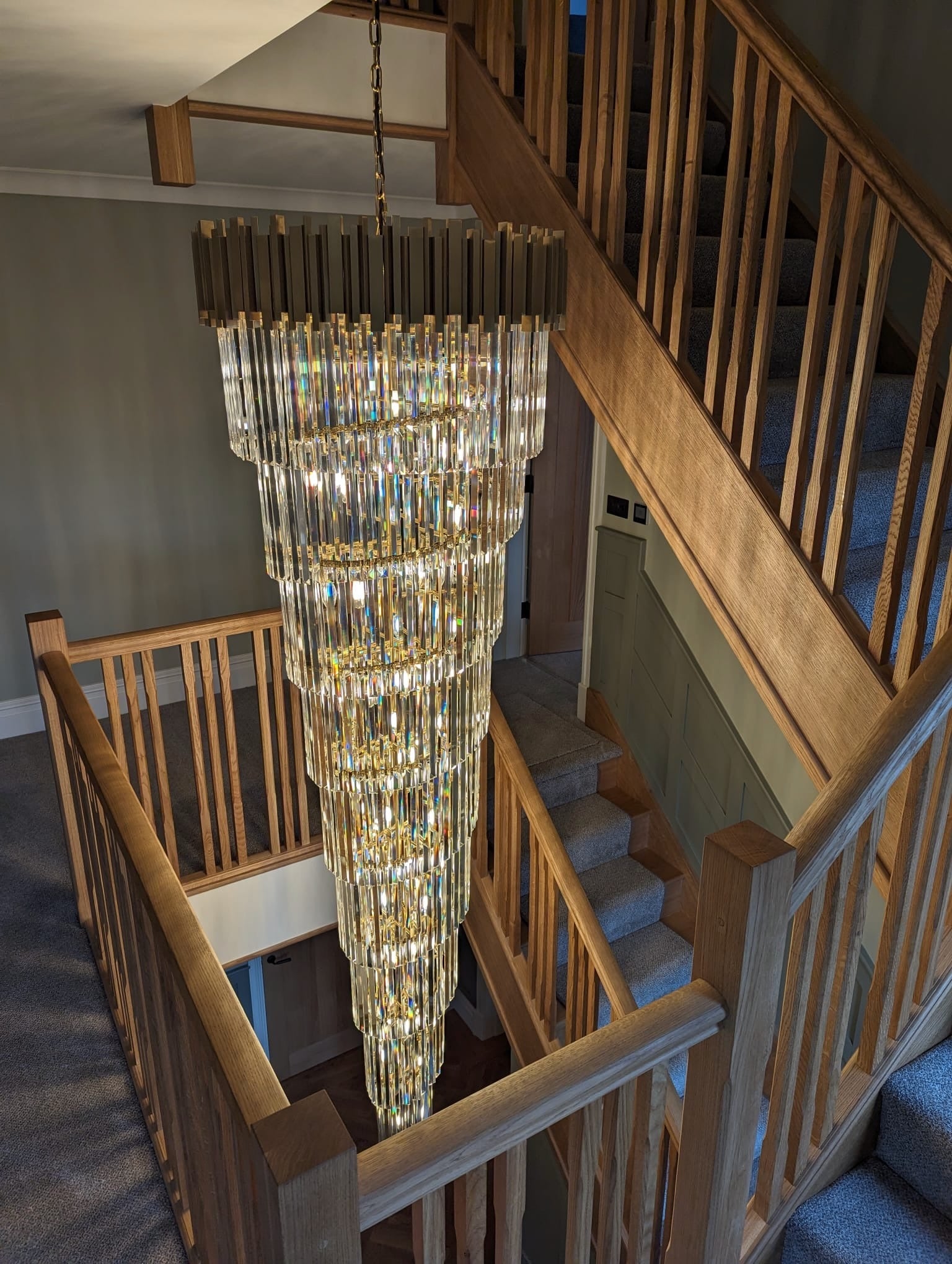 Boeotia spiral chandelier installed in wooden staircase setting