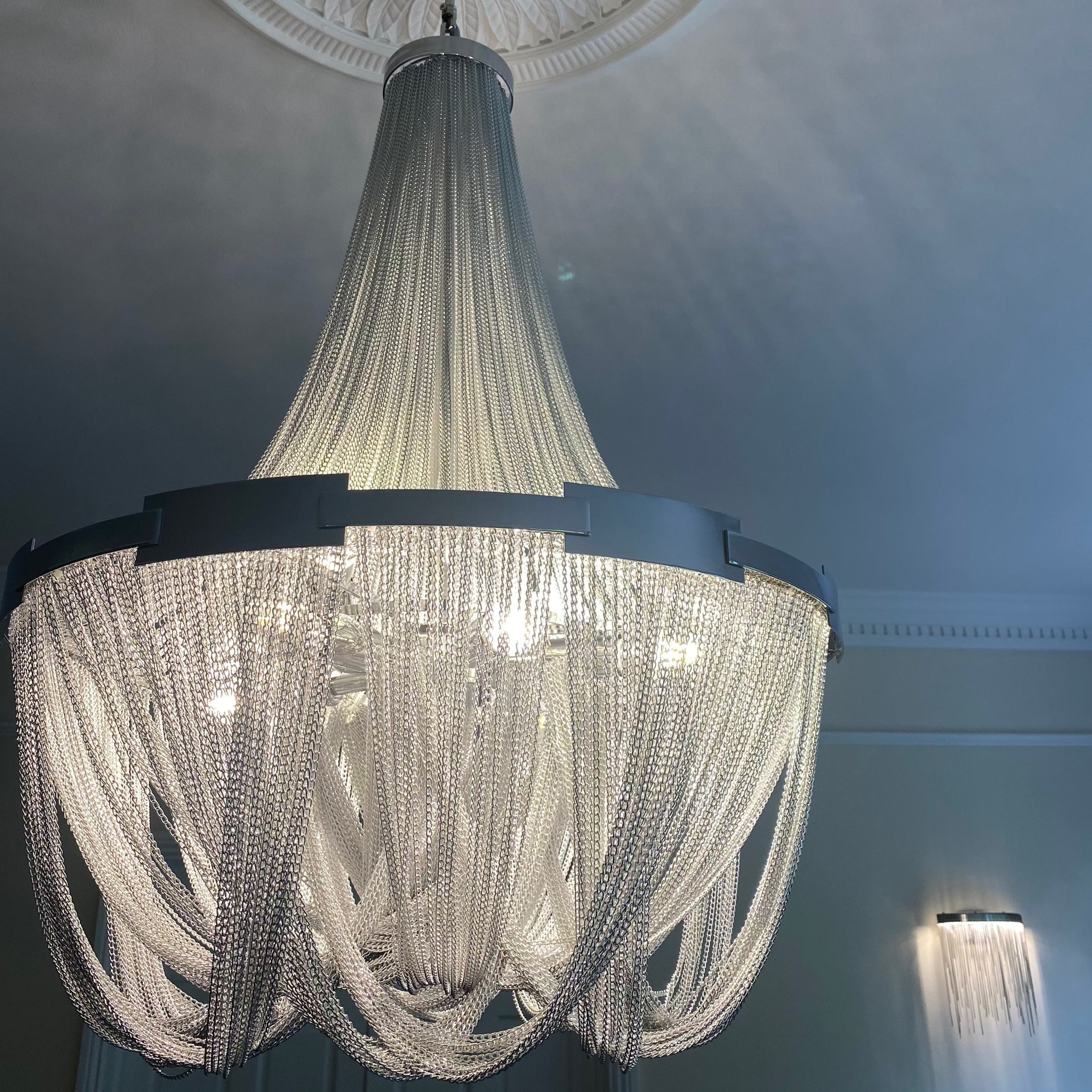 Cascading chain wall light paired with matching chandelier in UAE interior