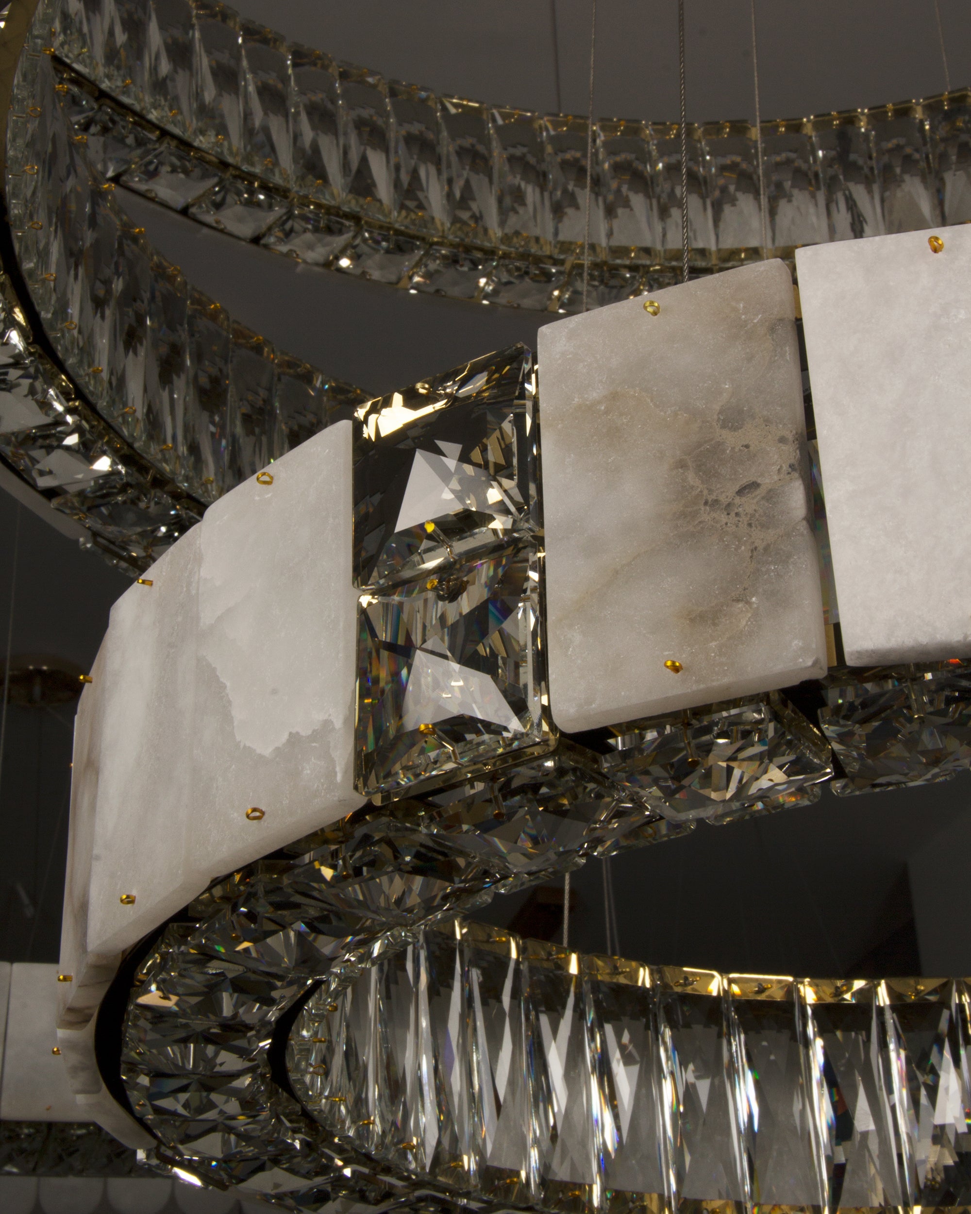 Close-up of natural marble panels forming the illuminated rings of the Helios Marble Trio Circular Chandelier