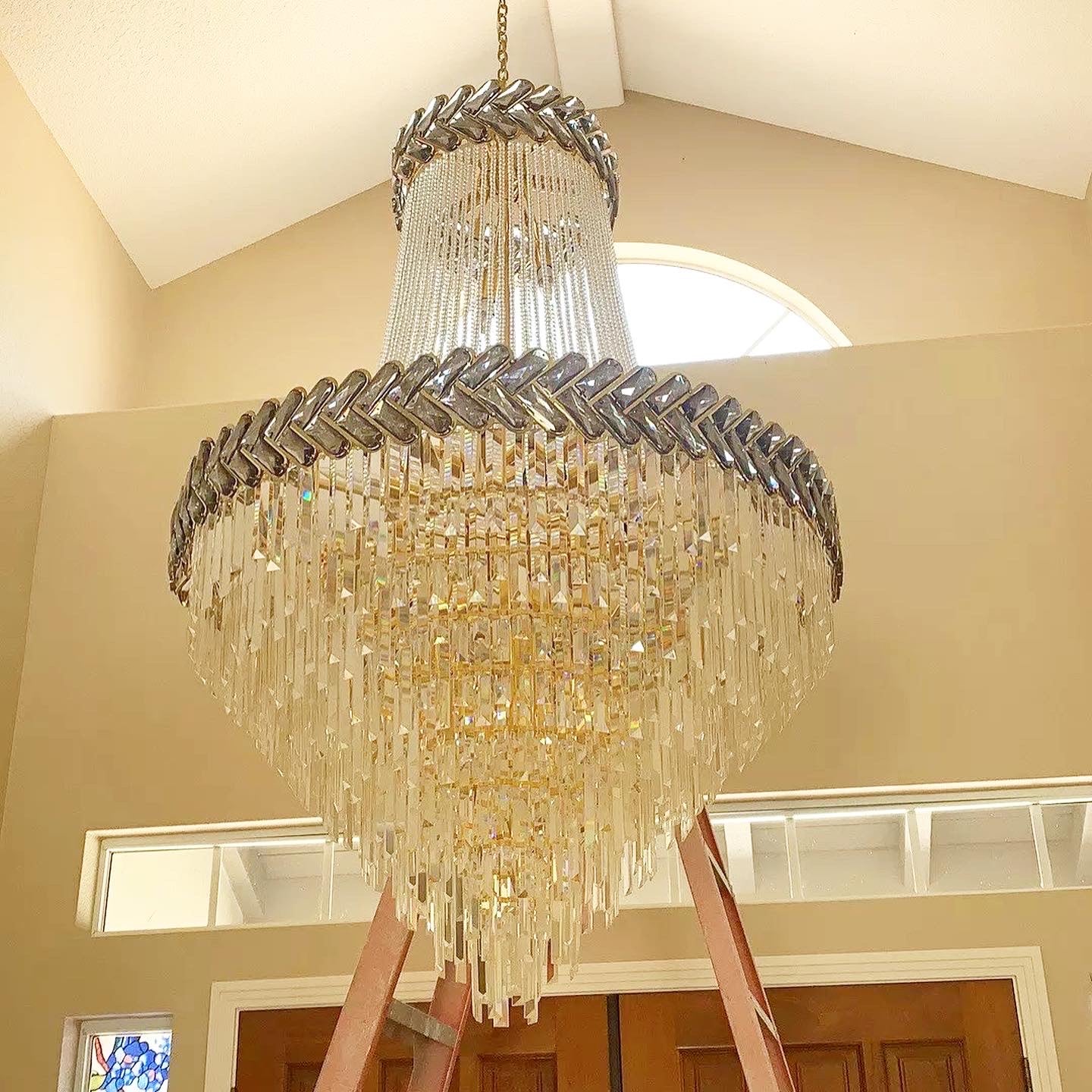 Two tier staircase chandelier with cascading crystal chains and refined luxury detailing