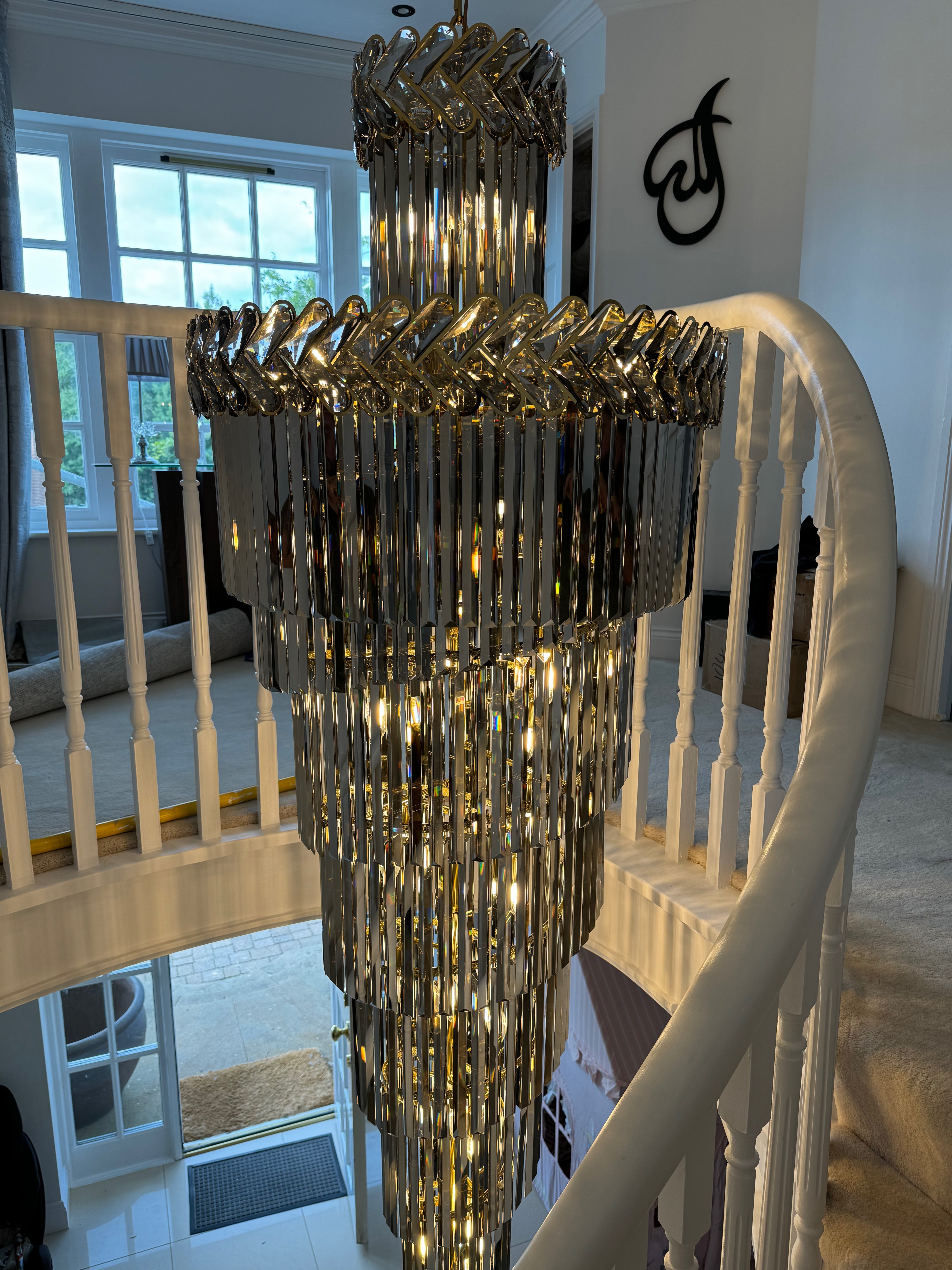Knightsbridge spiral staircase chandelier installed in a luxury double-height hallway with cascading crystal tiers