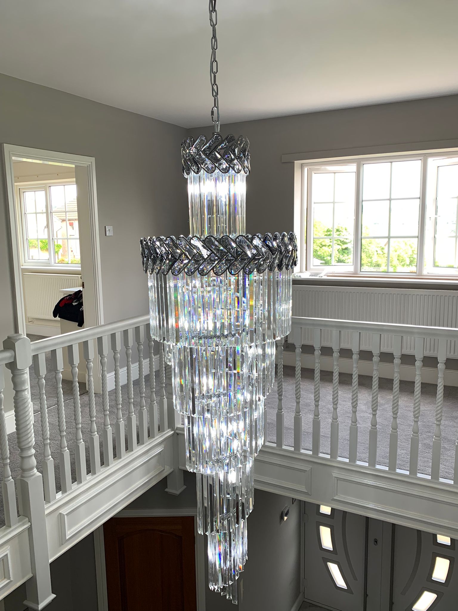 Spiral staircase chandelier viewed from upper landing with cascading crystals