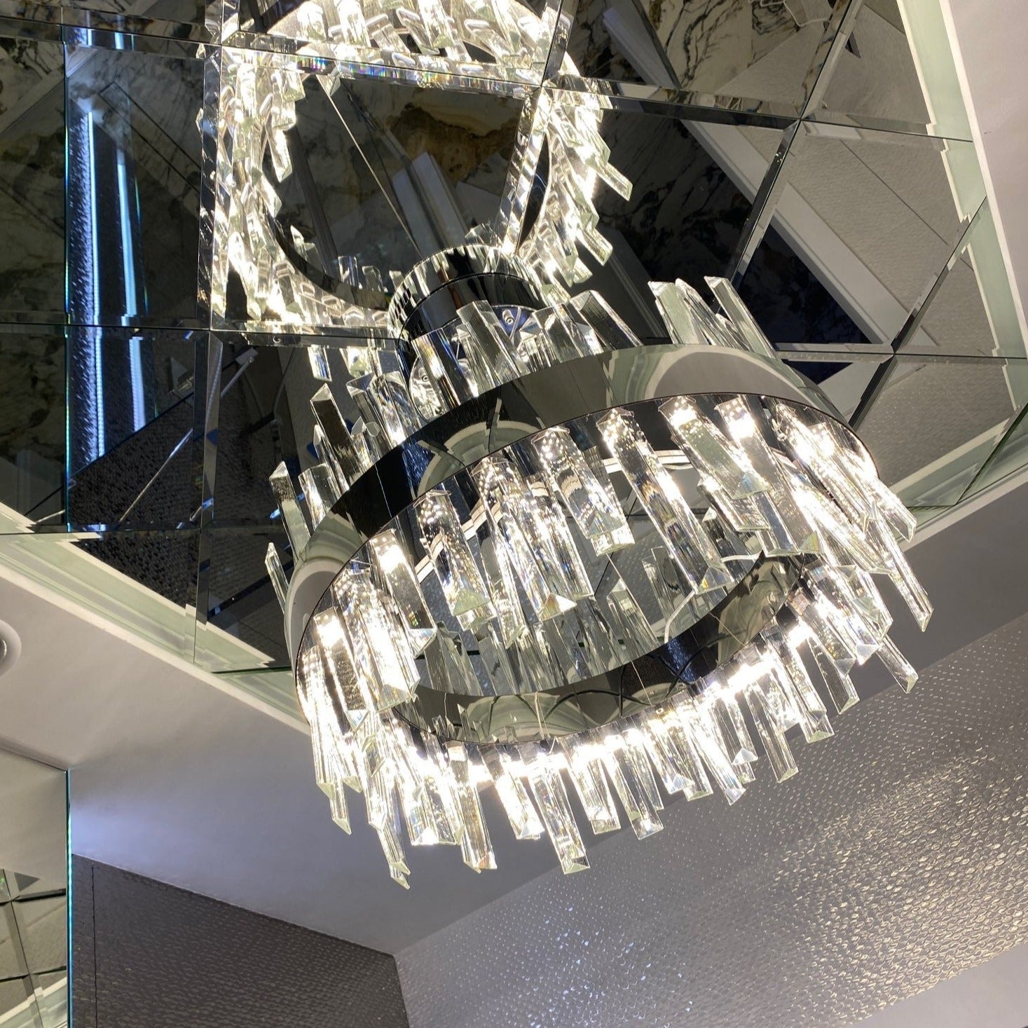 Angled view of circular chandelier highlighting layered crystal bars and reflective gold interior detail