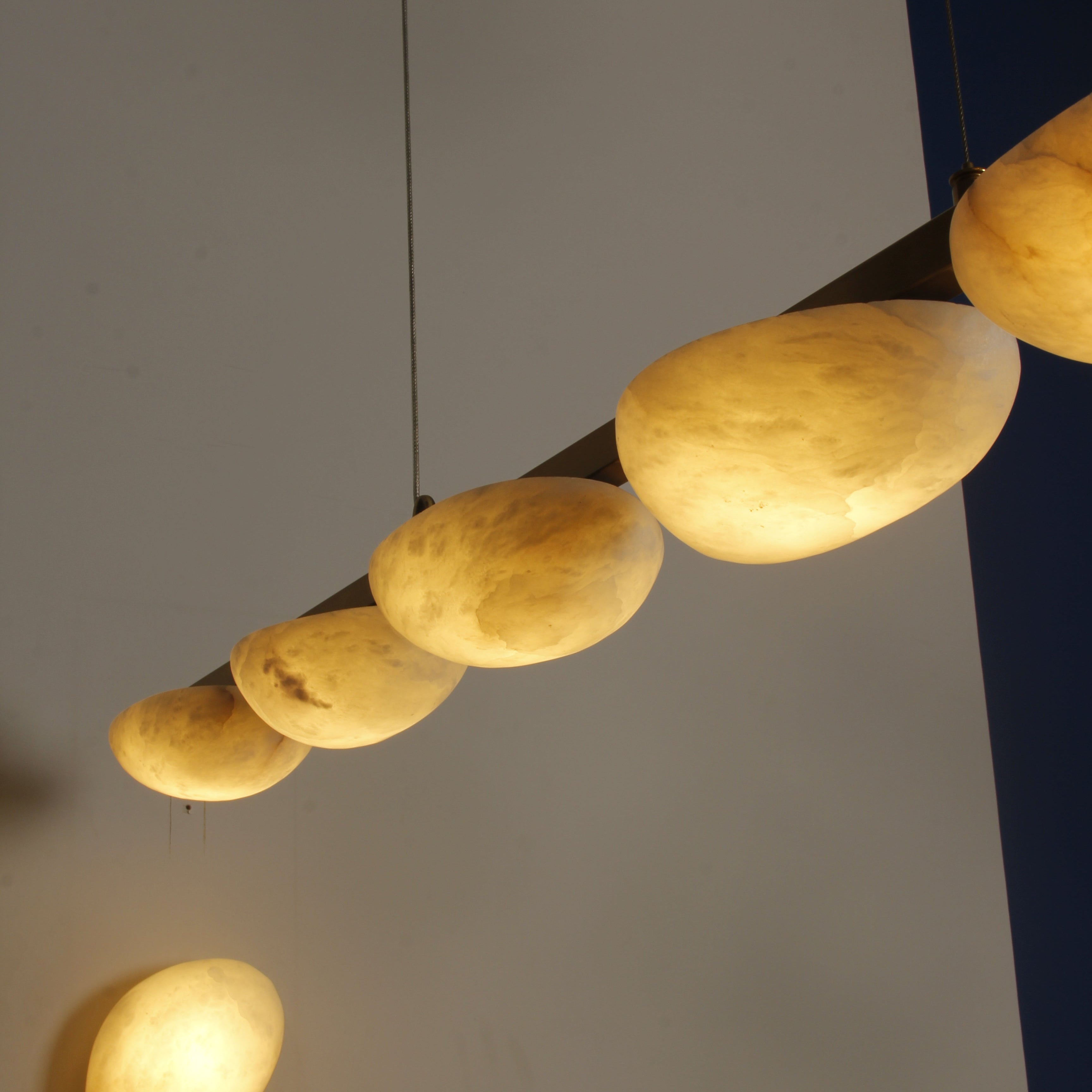 Modern marble rectangular chandelier suspended above dining table in UAE