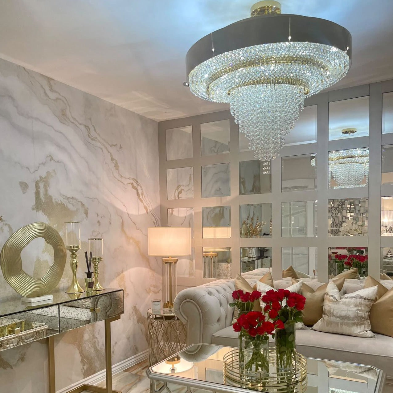 VORELLI® Champs Elysees circular crystal chandelier illuminating a luxury living room with mirrored panels and warm gold tones