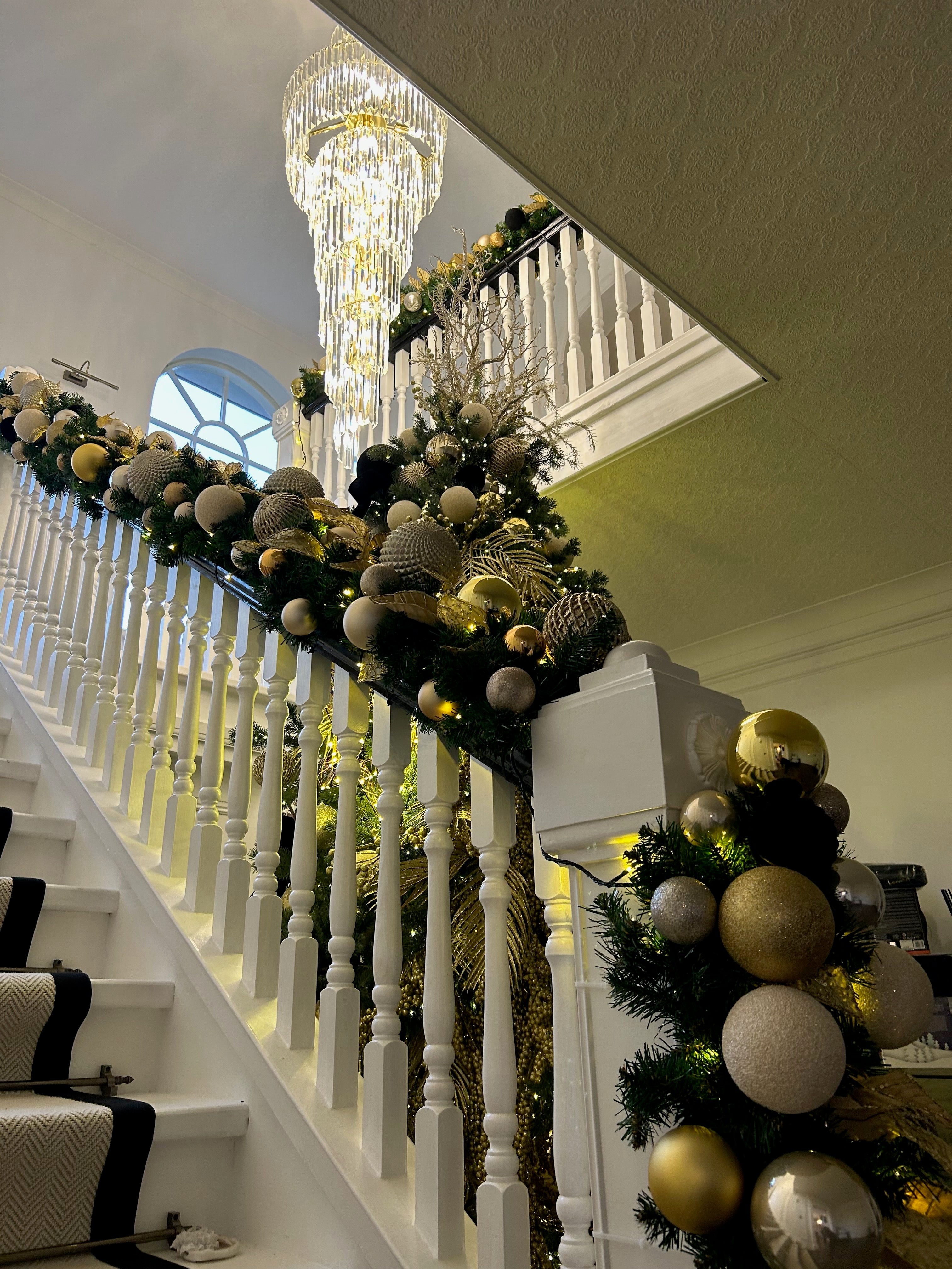 Illuminated diamond-cut crystal bars on the VORELLI® Manhattan spiral staircase chandelier creating a luxury glow