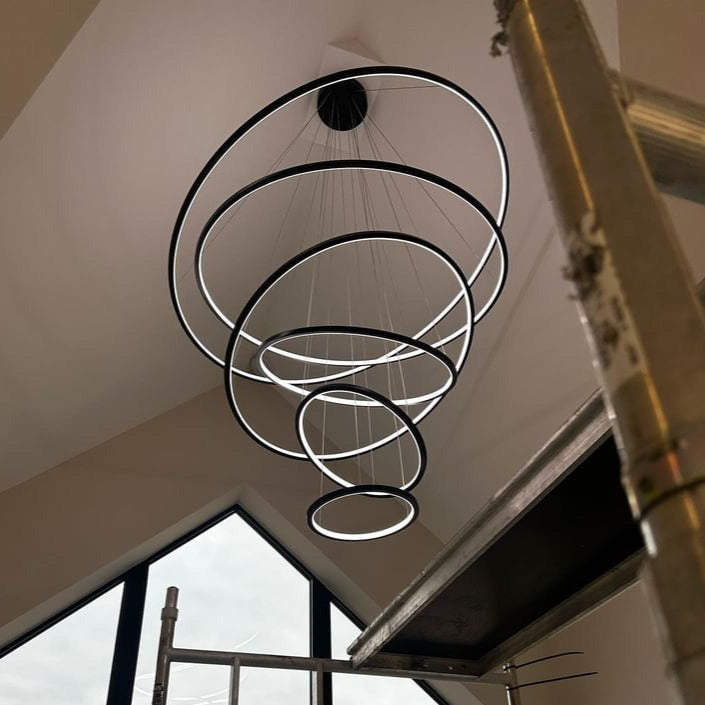 Upward architectural view of concentric LED rings forming the Marcello staircase chandelier by VORELLI