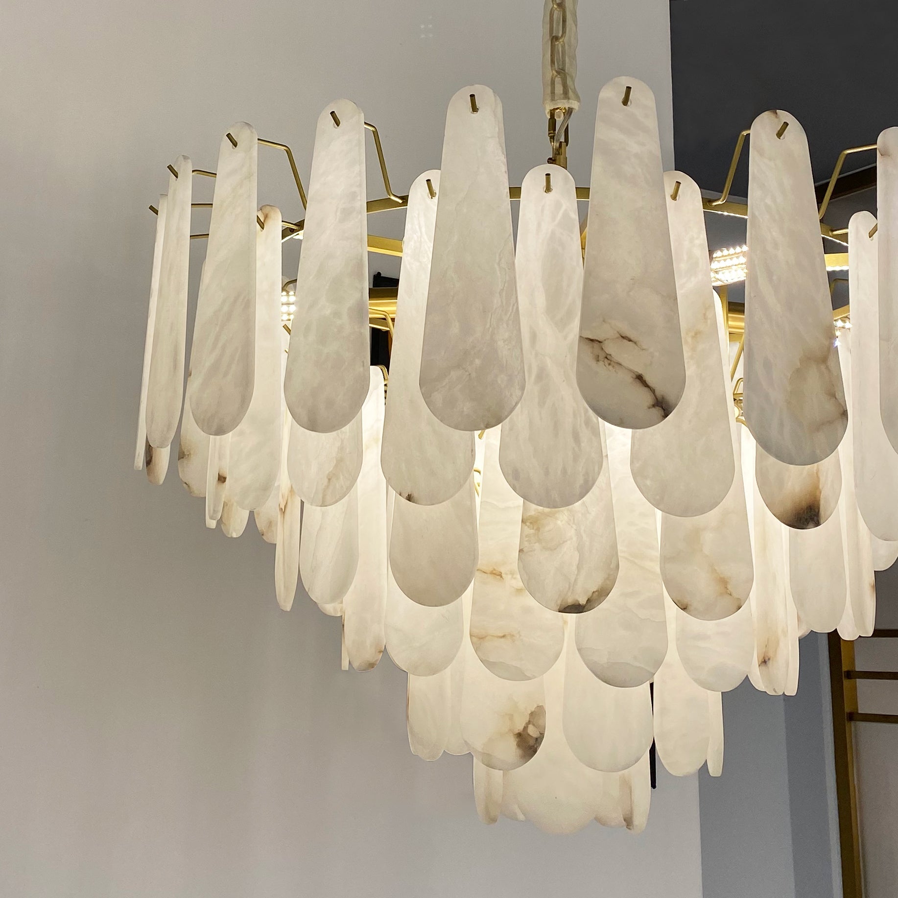 Close-up of softly glowing layered marble pieces on the VORELLI Maretto circular chandelier creating warm ambient lighting