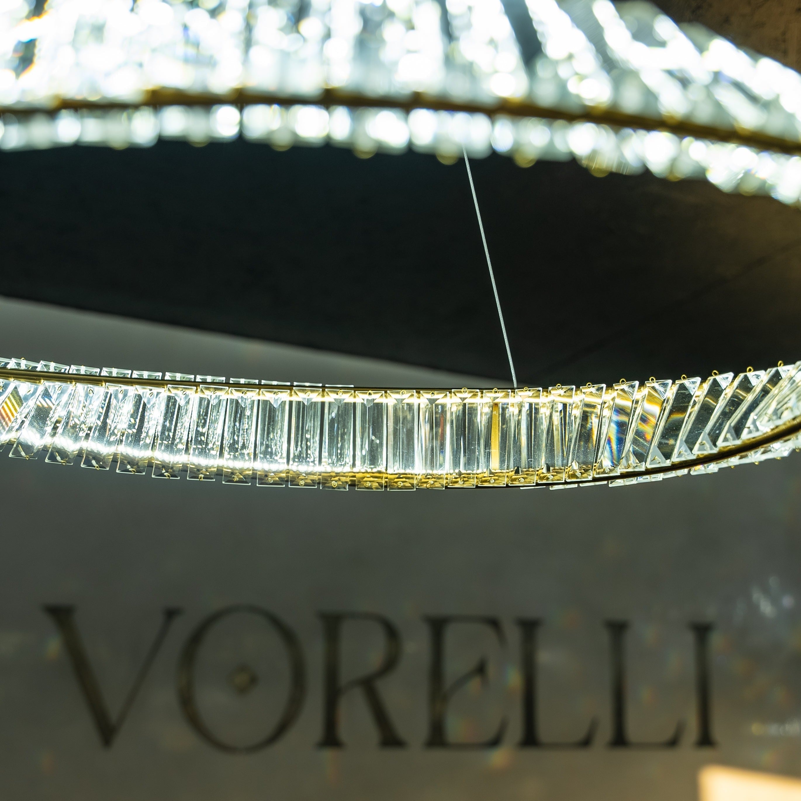 Detailed view of illuminated crystal bars forming the twisted circular structure of the VORELLI Melia chandelier