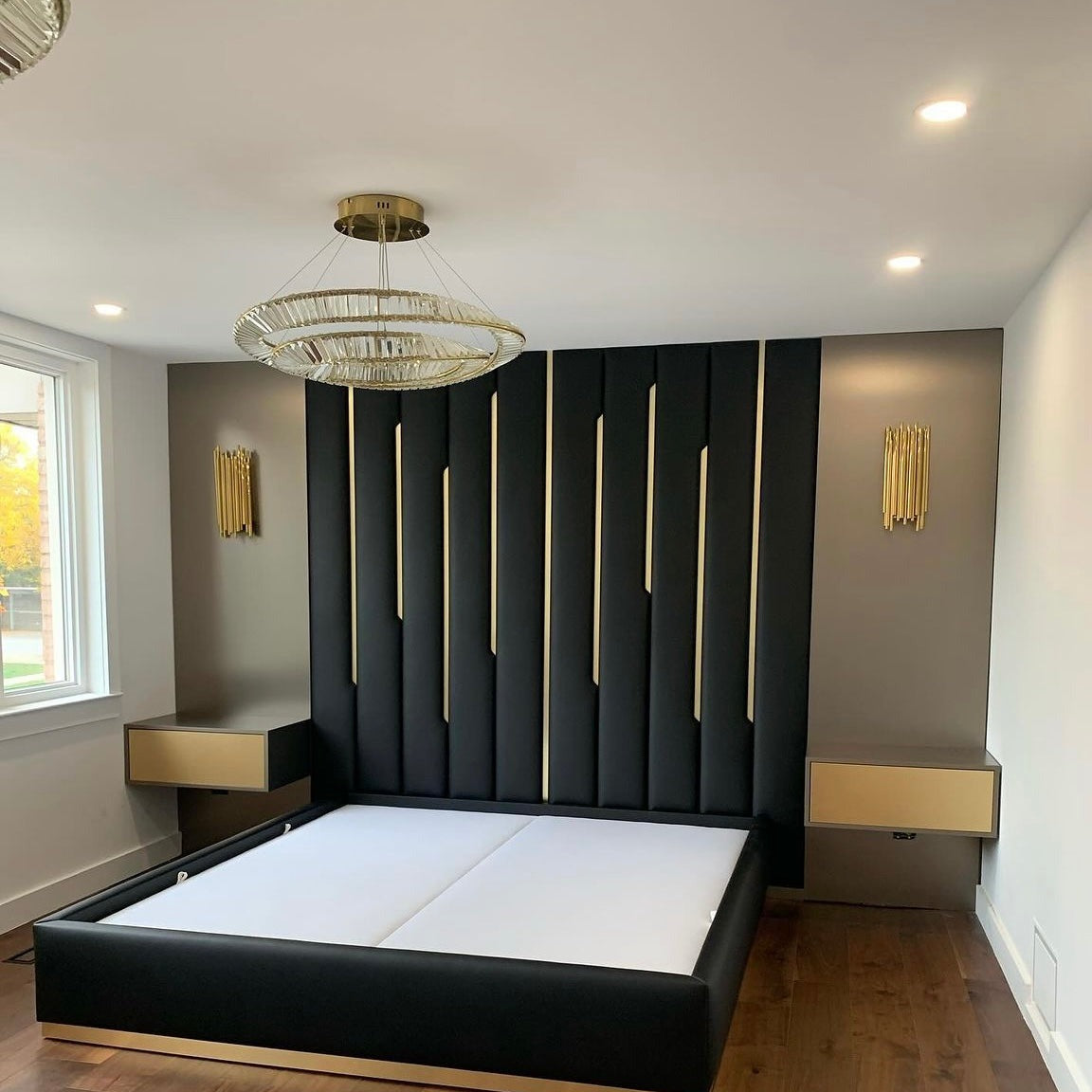 Angled view of the VORELLI Melia double circular chandelier creating warm ambient lighting in a contemporary bedroom