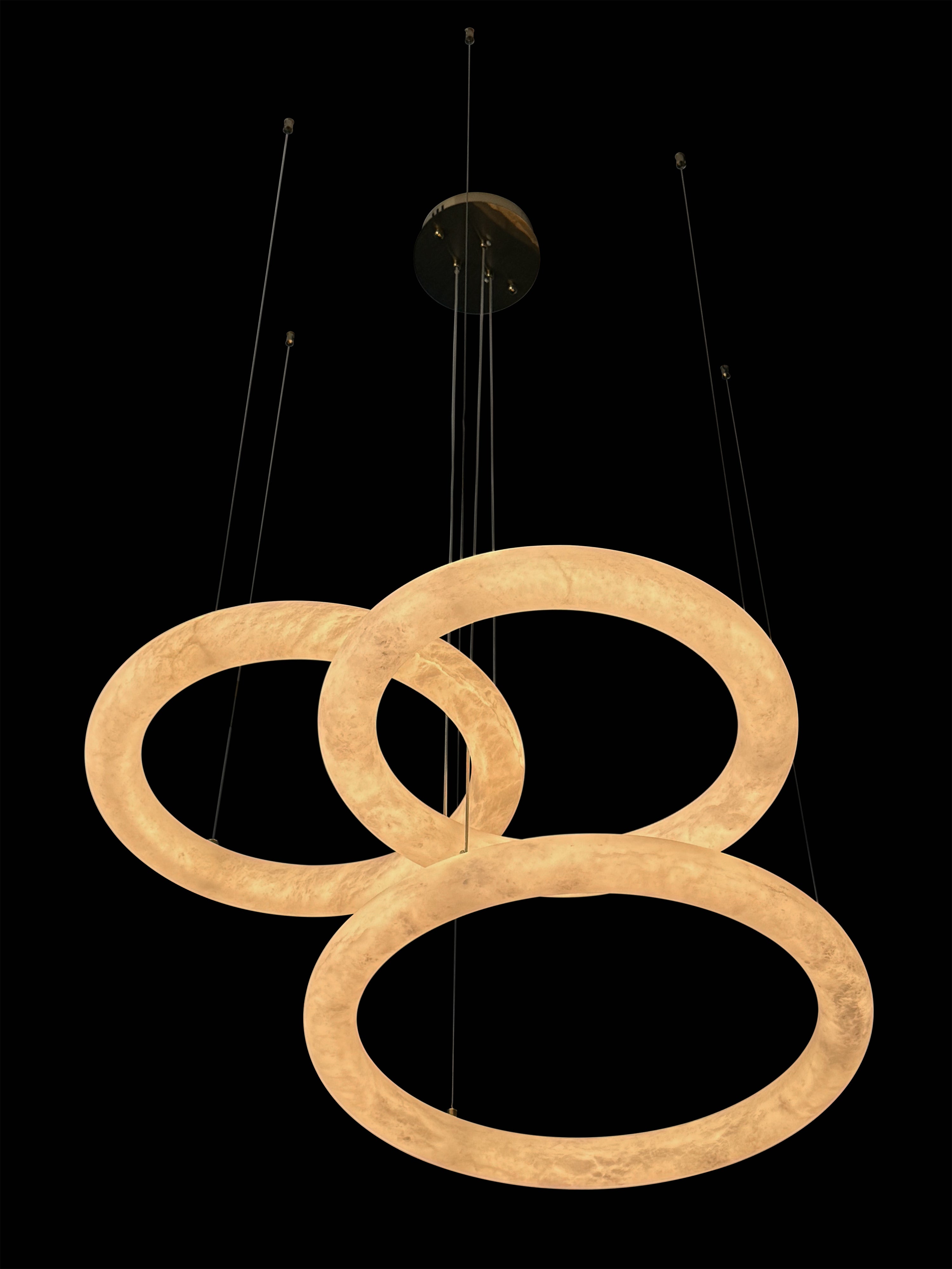 Side angle of the Cavani Marble Trio Circular Chandelier showing its sculptural illuminated marble rings.