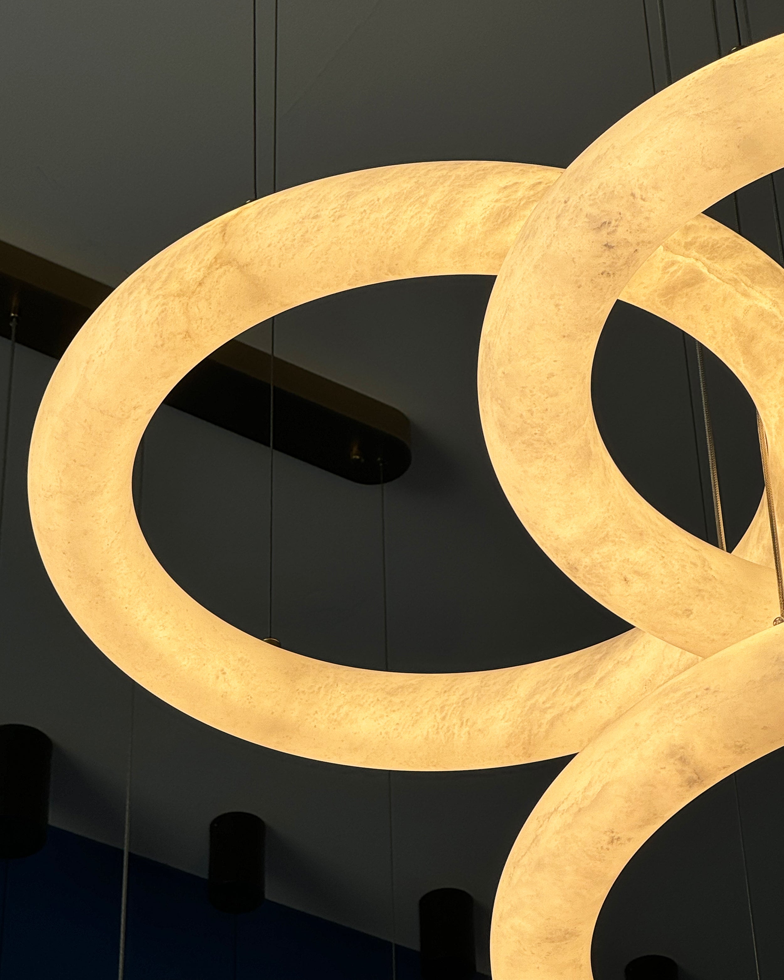 Detailed view of a marble ring on the Cavani Marble Trio Circular Chandelier showing natural veining and warm illumination.