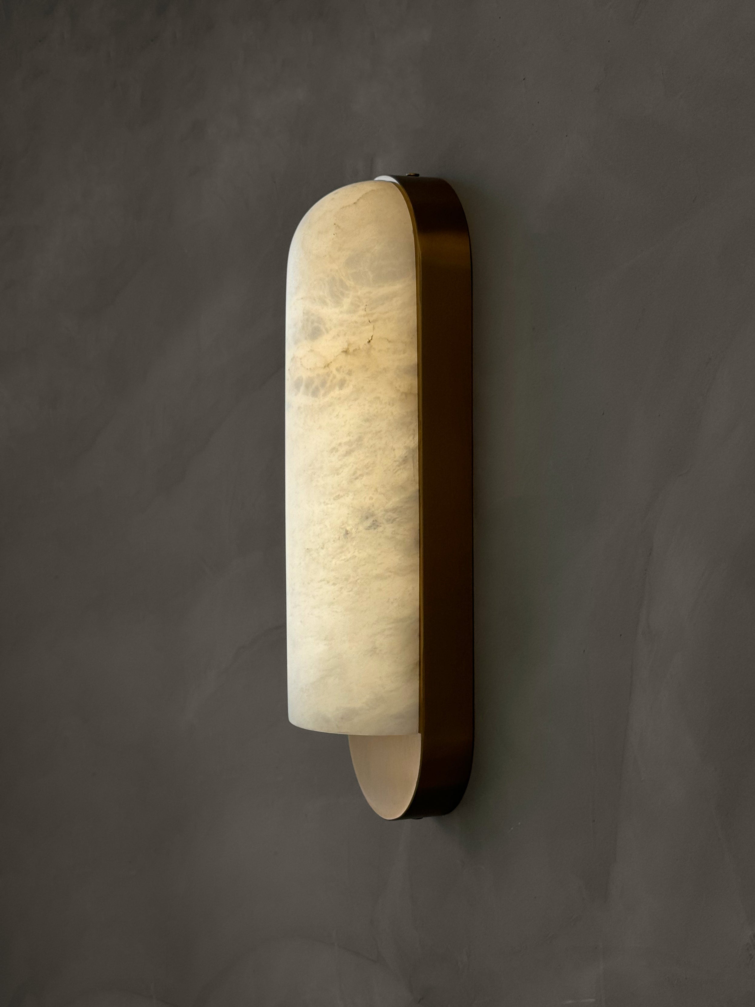 Side profile of Formello marble wall light showing curved form