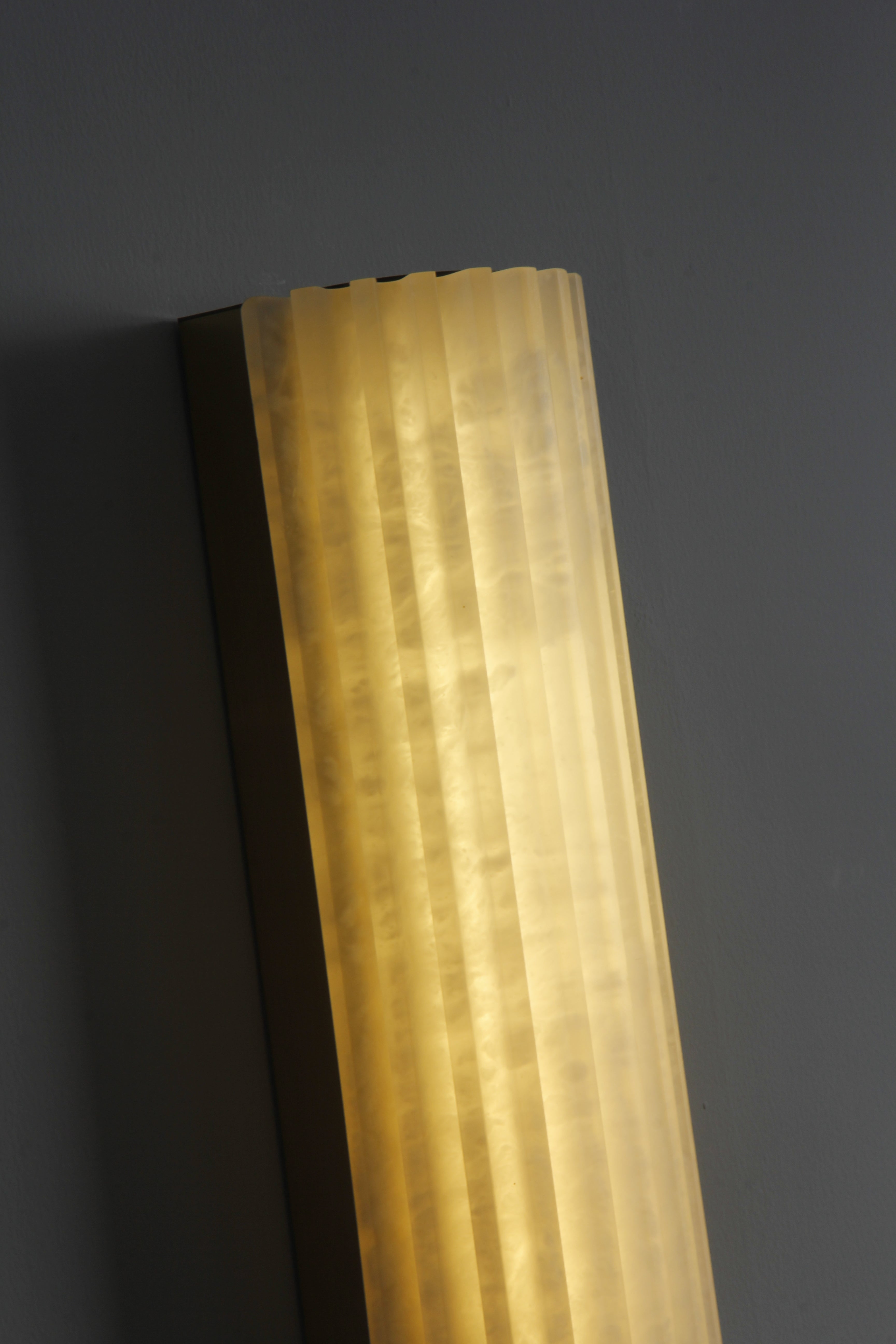 Slim vertical marble wall sconce profile with soft glowing diffusion