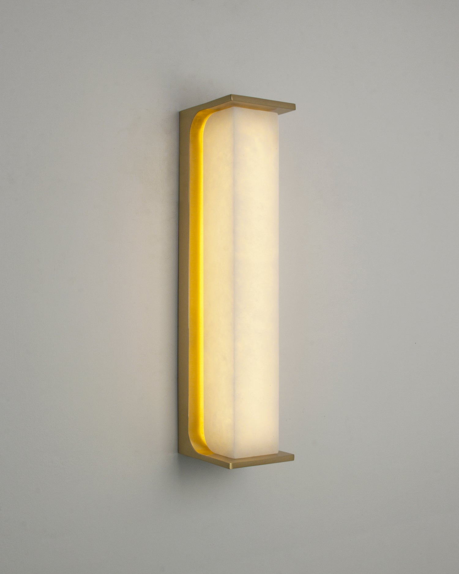 Warm diffused illumination through the marble surface of the VORELLI Matera wall light highlighting natural tone and soft ambient lighting