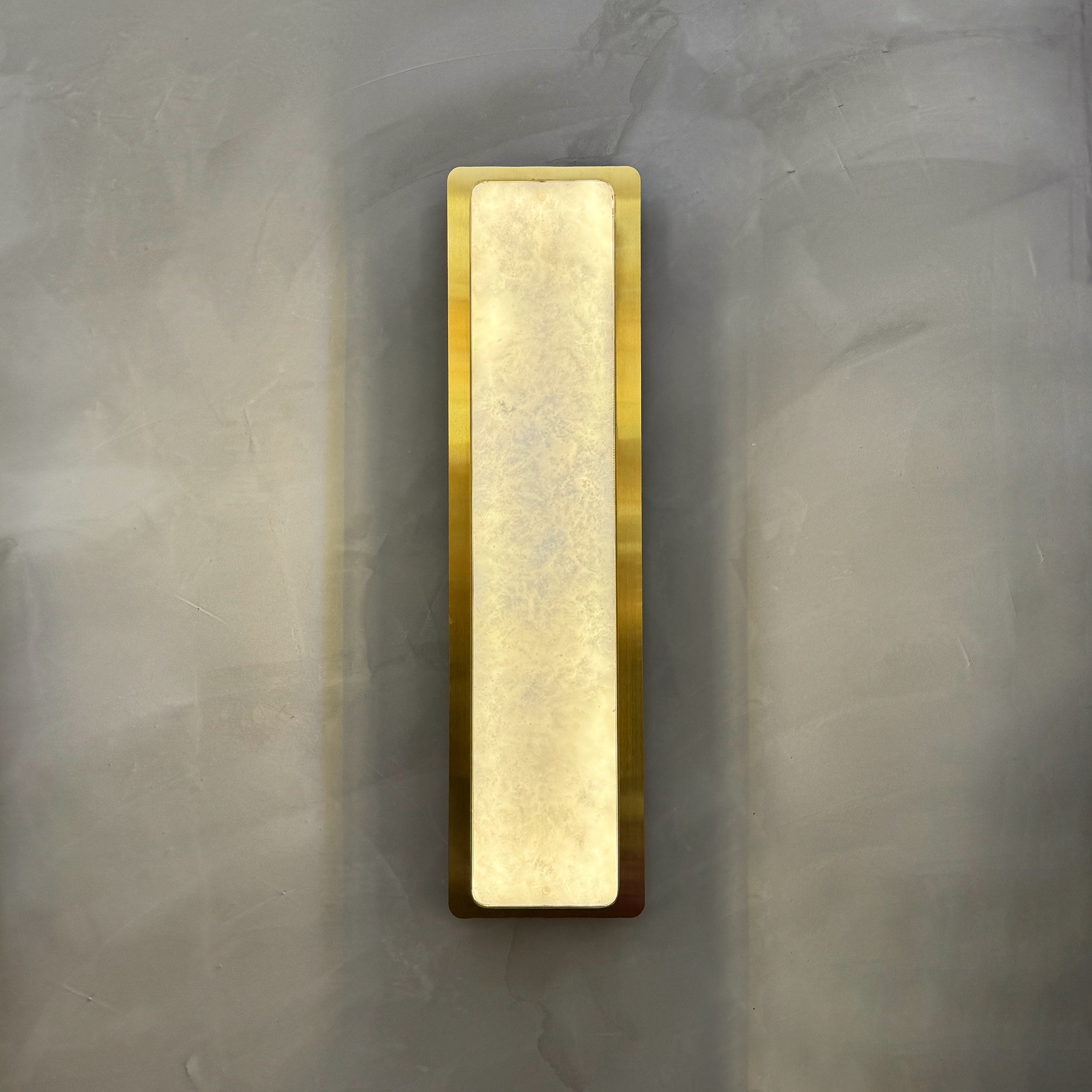 Salerno modern marble wall sconce mounted on textured wall creating clean architectural silhouette