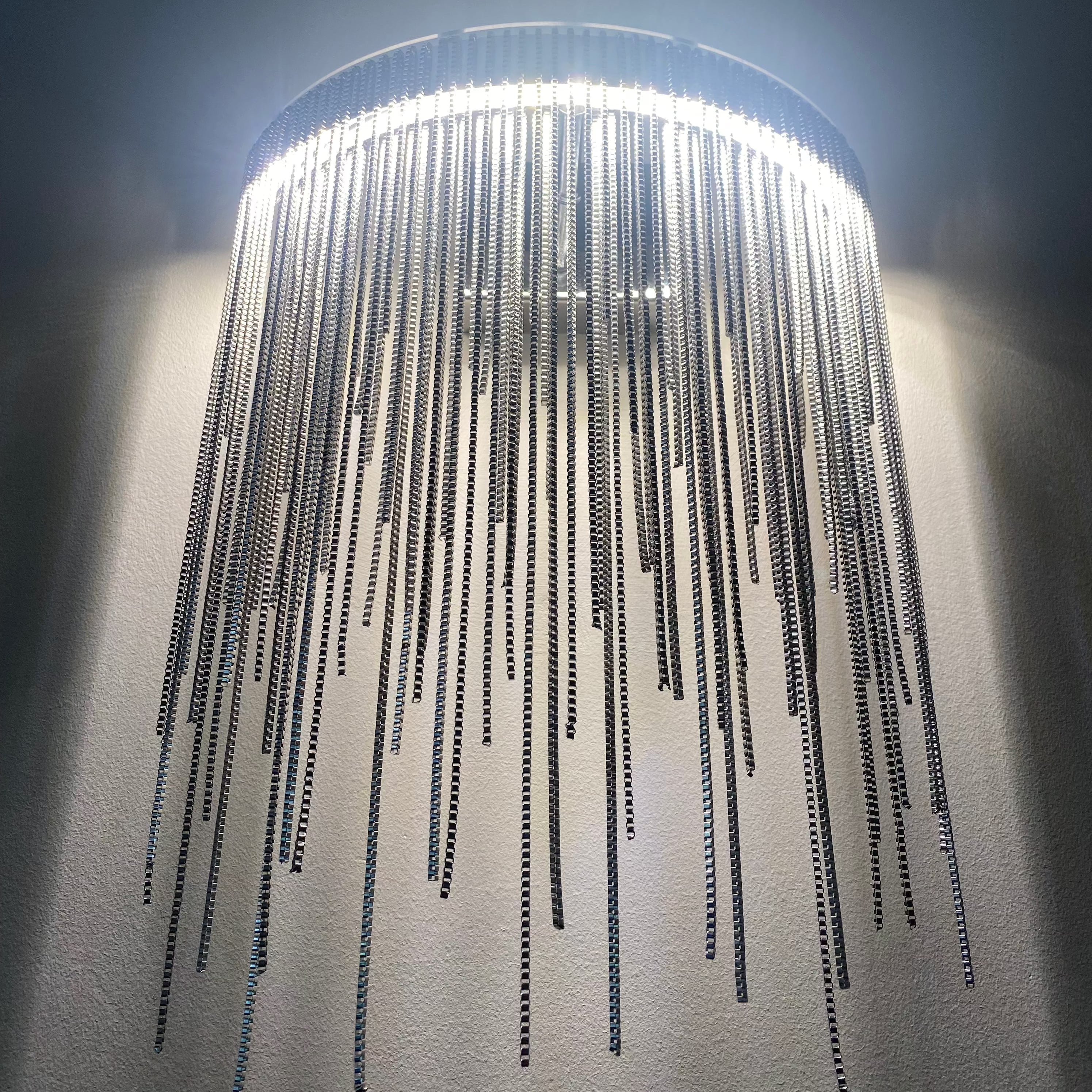 Upward angle of cascading metal chain wall light detail
