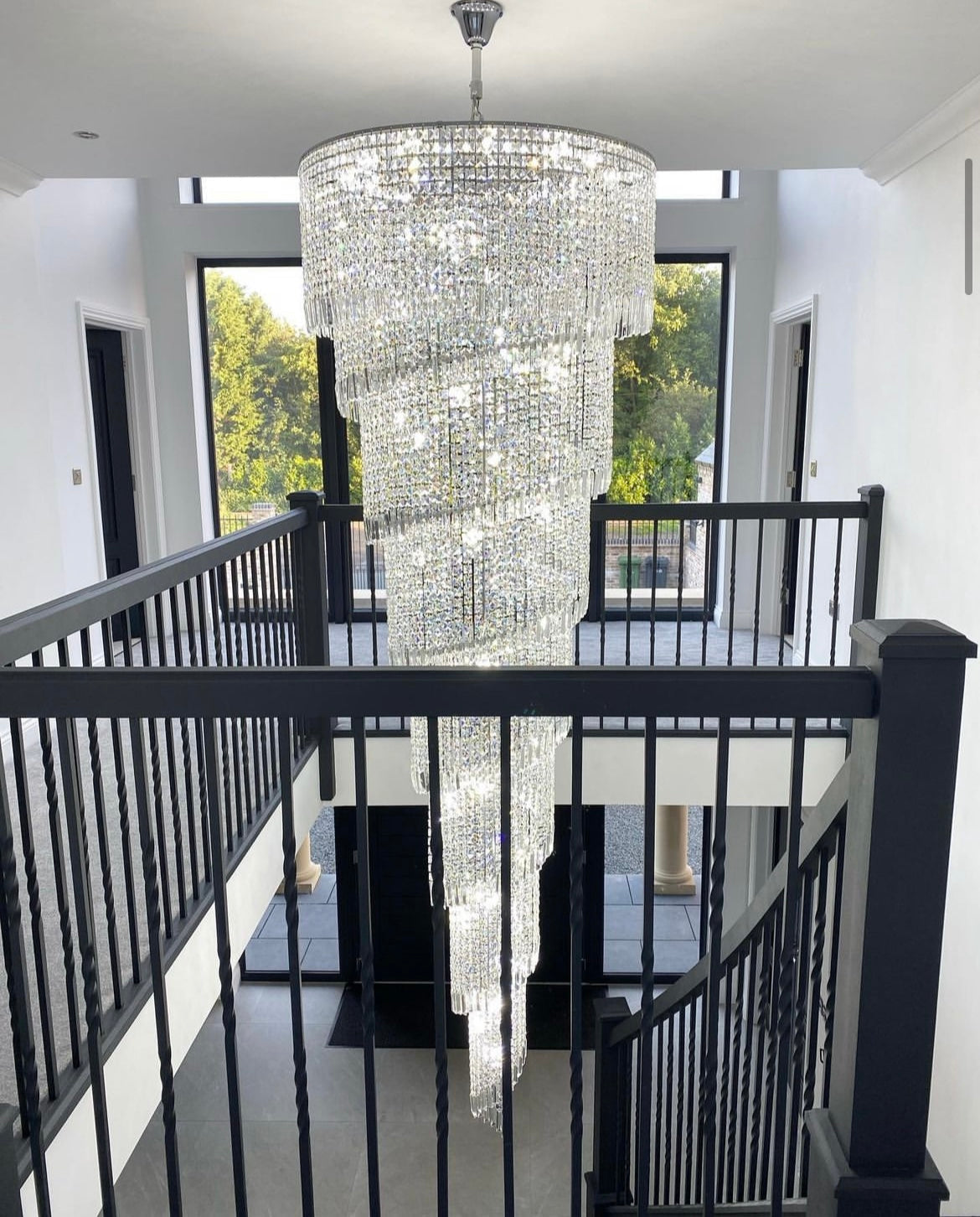 Side view of Basiglio spiral crystal chandelier in double-height staircase