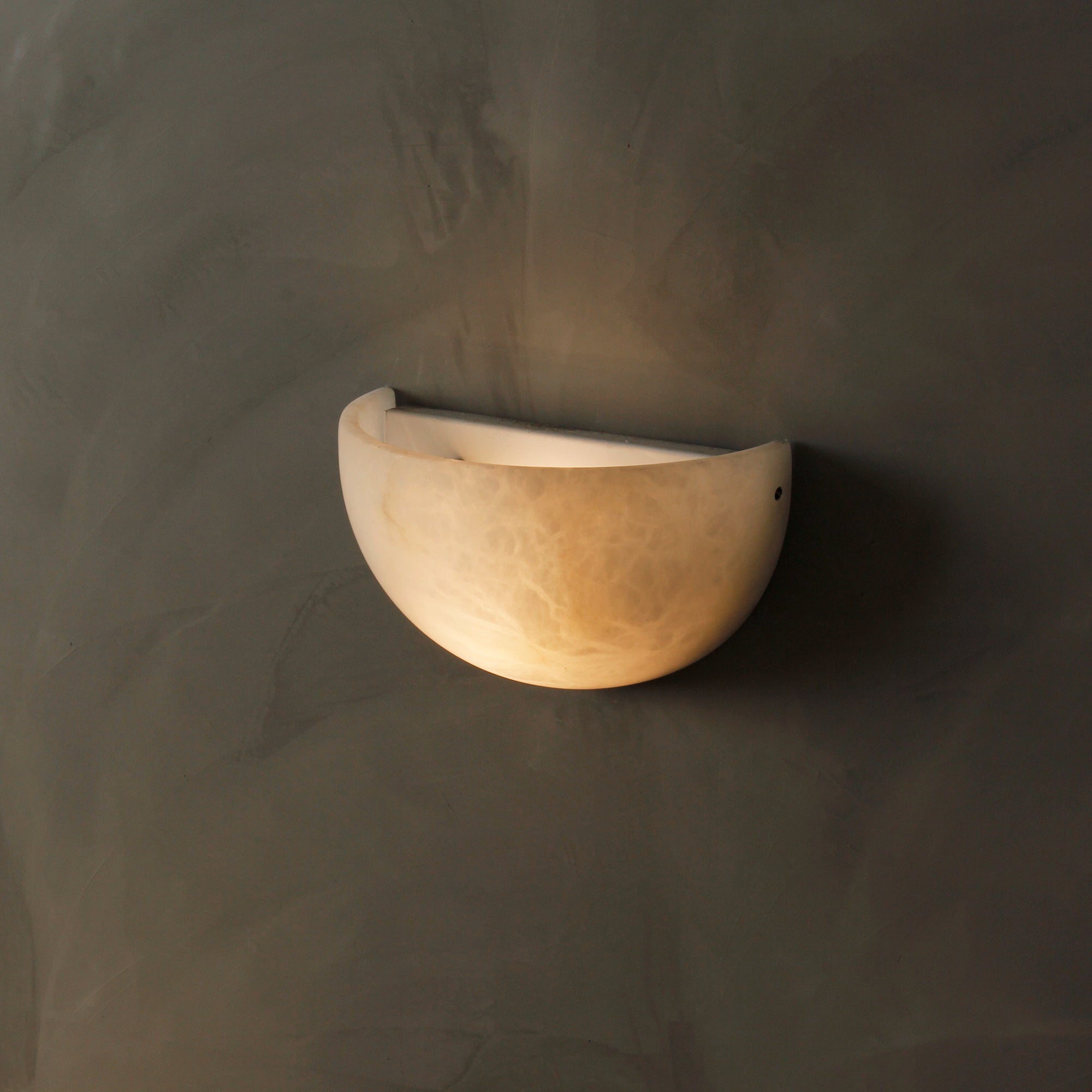 Side profile of Belluno half-bowl marble wall light in natural stone