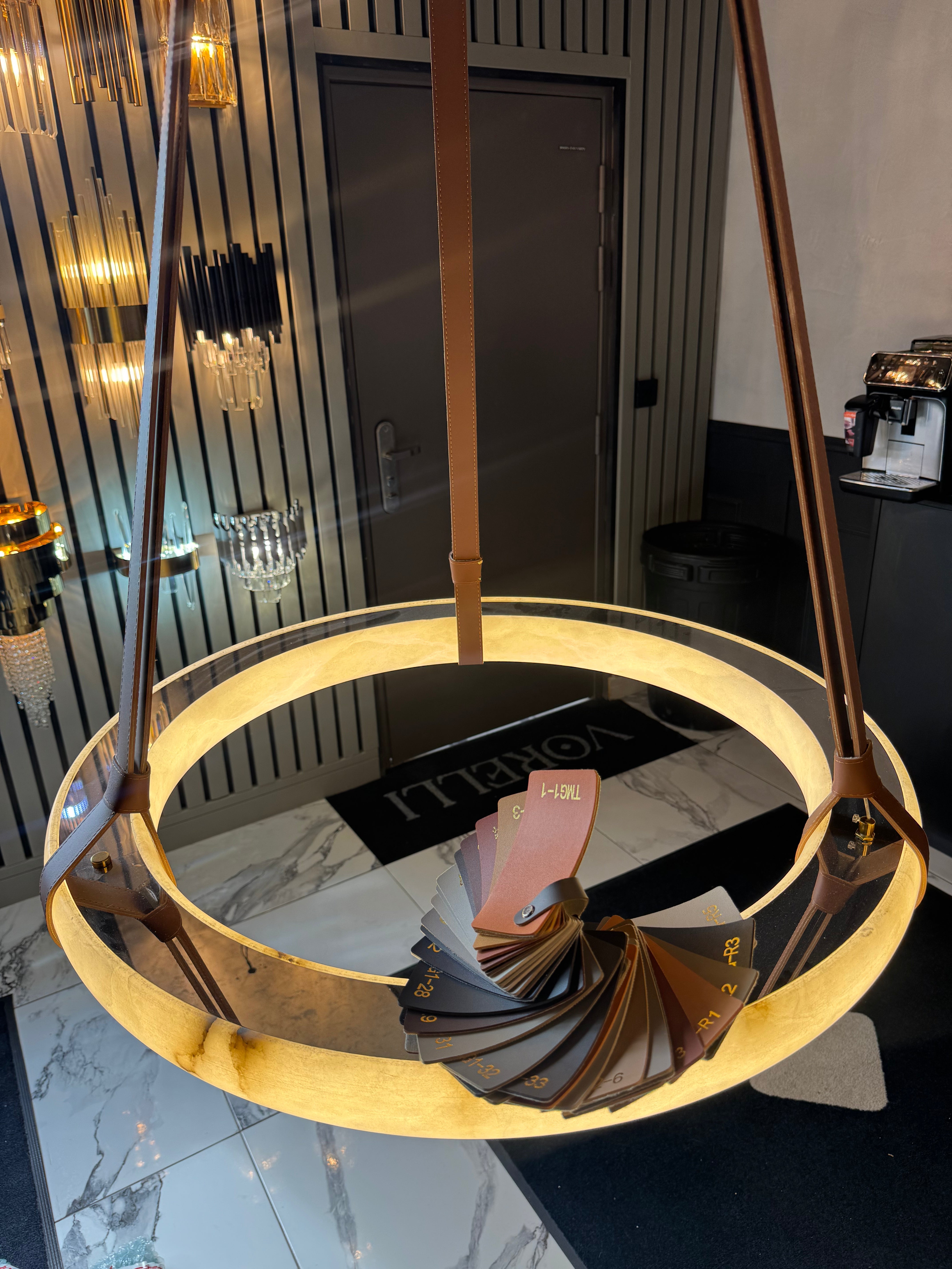 Angled view of illuminated Botticino marble circular chandelier