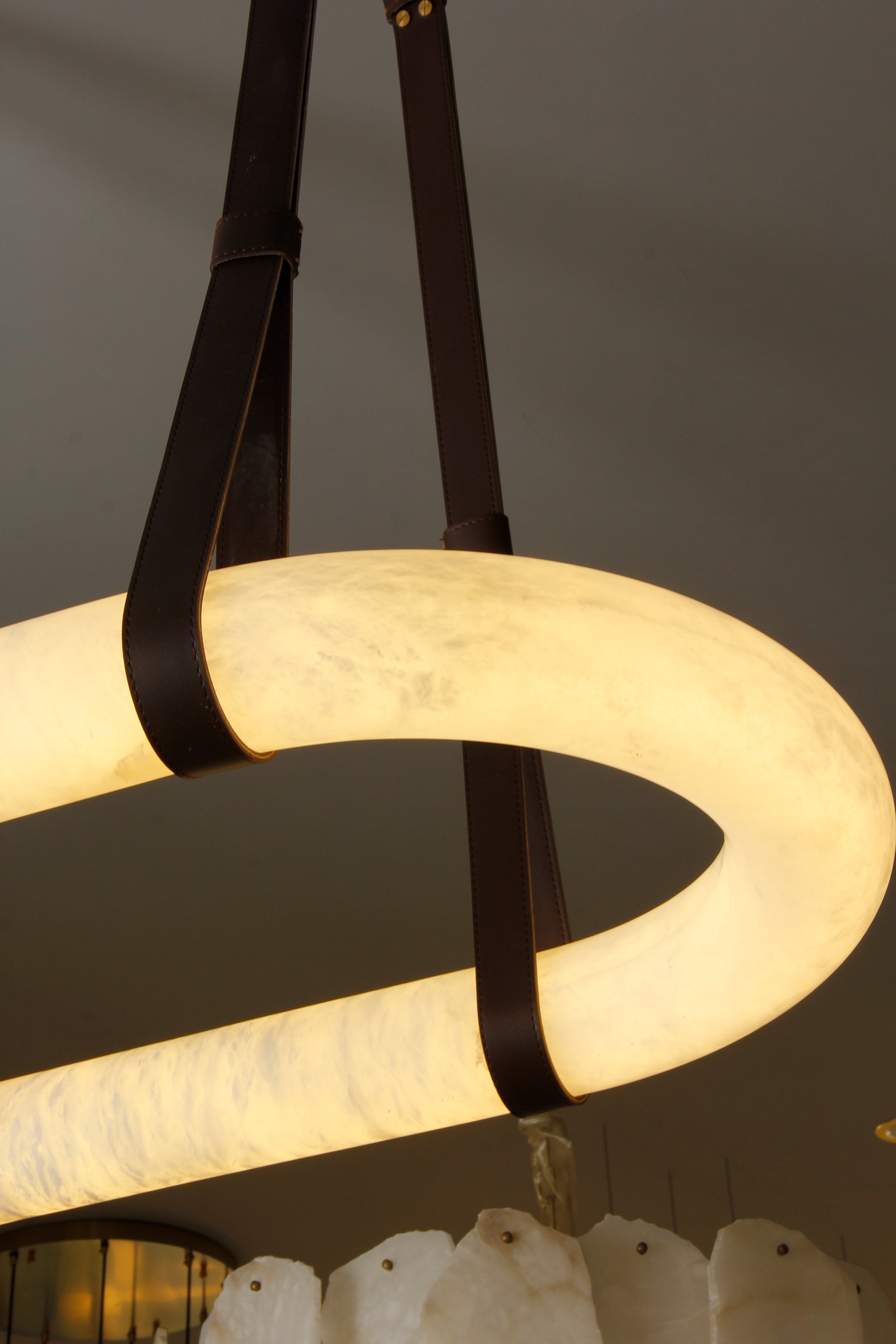 Angled view of illuminated Botticino marble rectangular chandelier