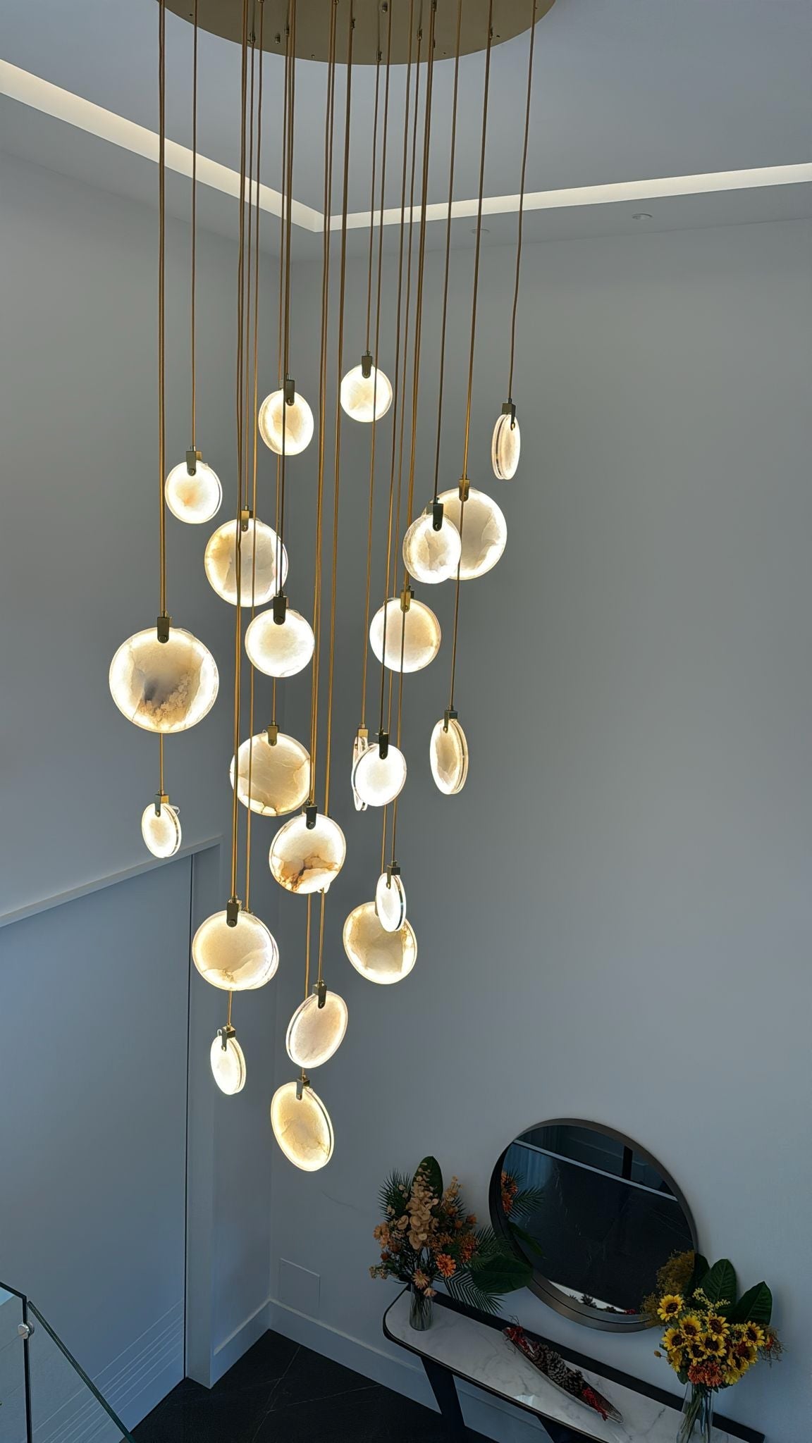 Cascading Calacatta marble discs forming a luxury staircase chandelier installation.