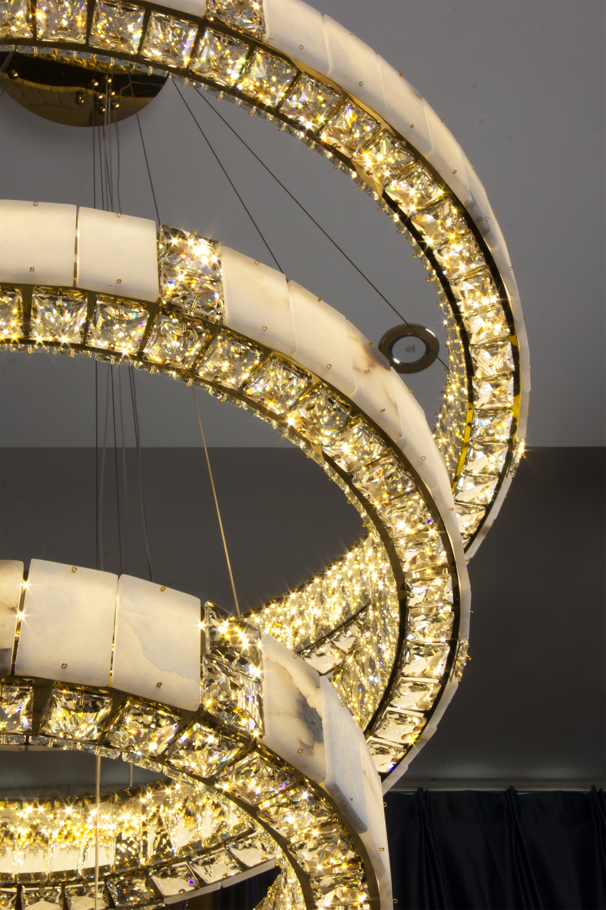 Close angled view of luminous marble rings and crystal illumination on the Helios Marble Trio Circular Chandelier