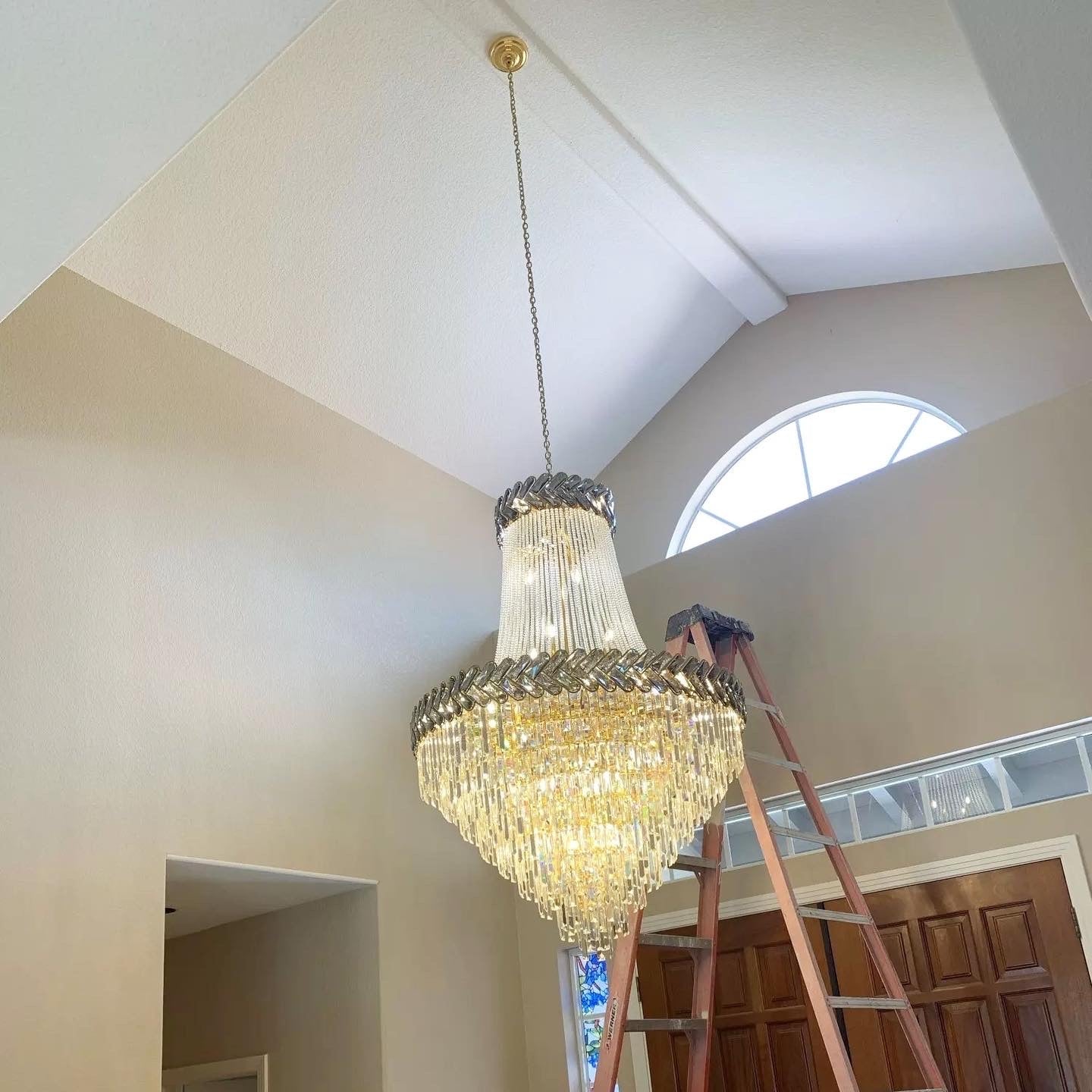 Tall crystal staircase chandelier creating elegant illumination in grand interior space
