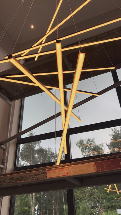 Modern linear LED staircase chandelier suspended above stairwell creating architectural statement lighting