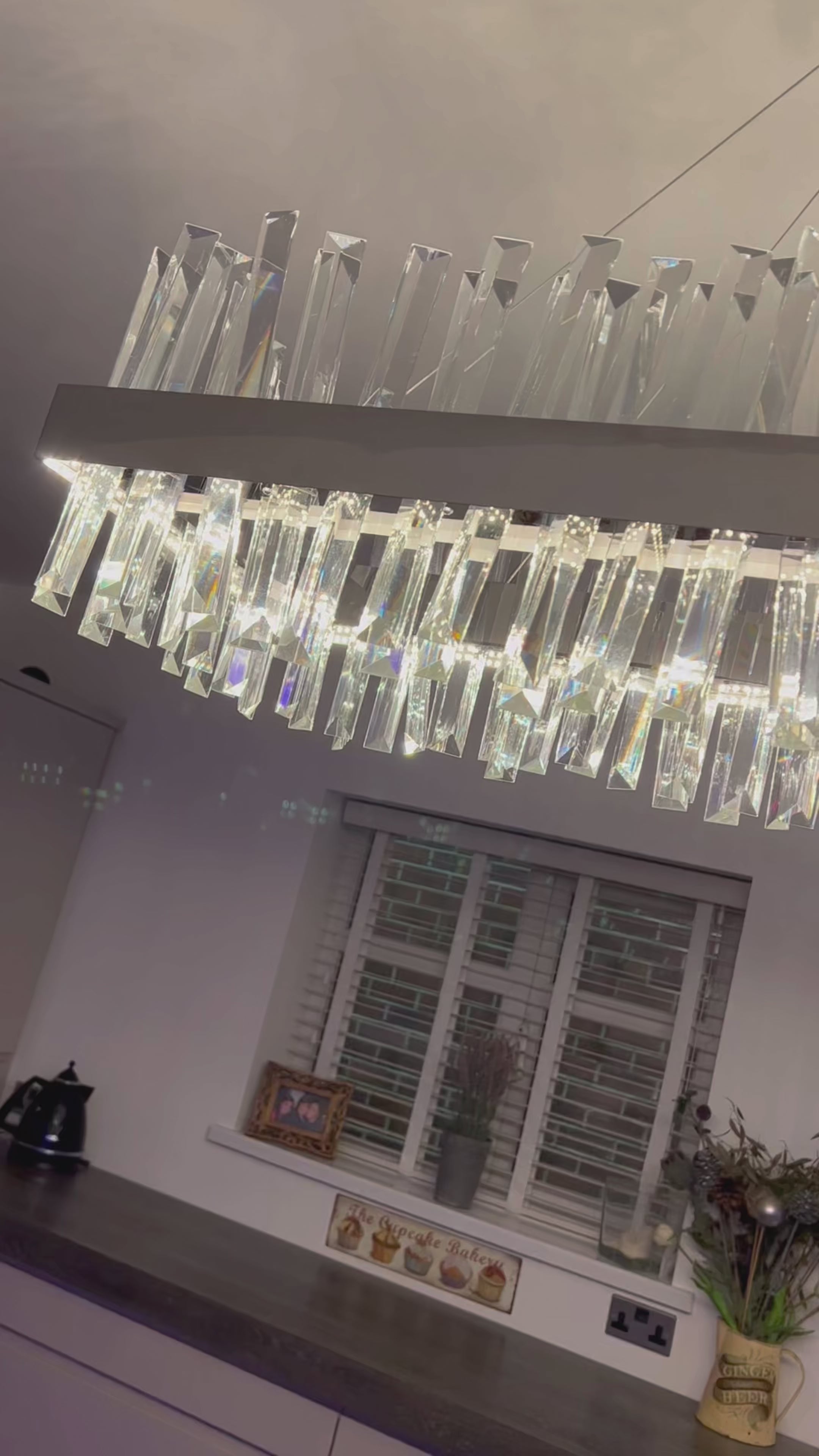 Rectangular crystal bar chandelier suspended above a contemporary interior from an angled perspective