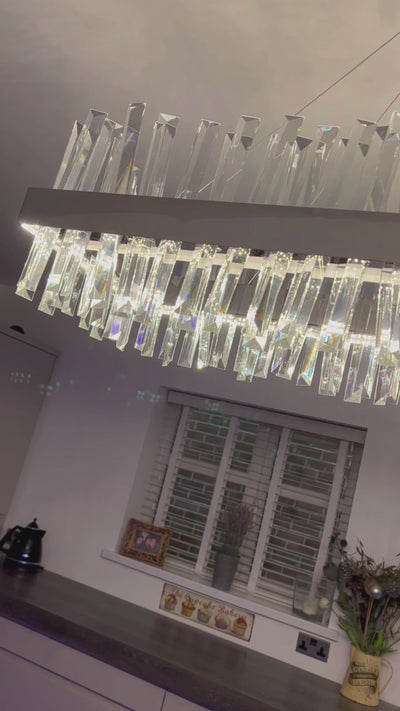 Rectangular crystal bar chandelier suspended above a contemporary interior from an angled perspective