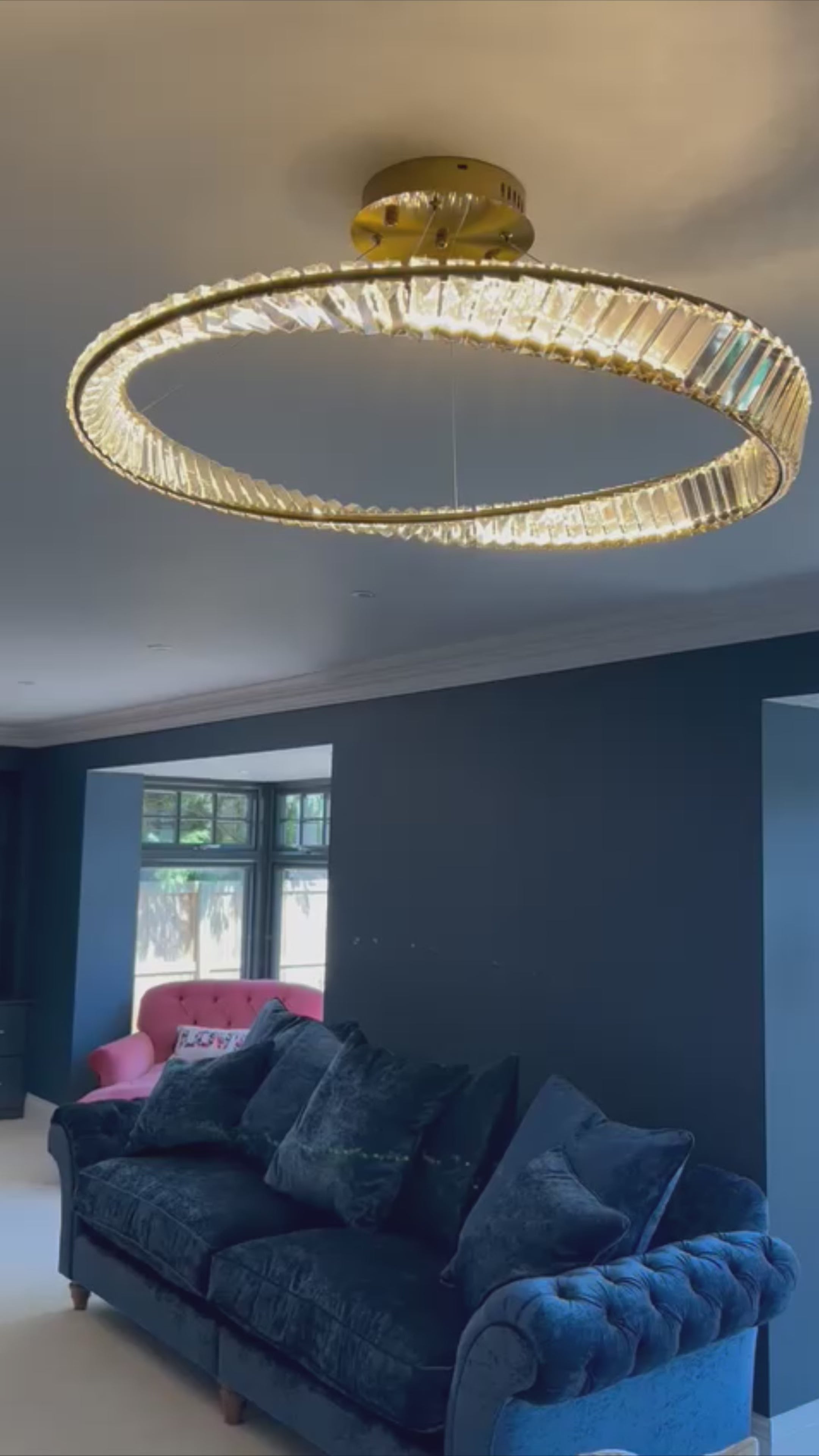 Elegant VORELLI Melia circular crystal chandelier illuminating a contemporary living room interior