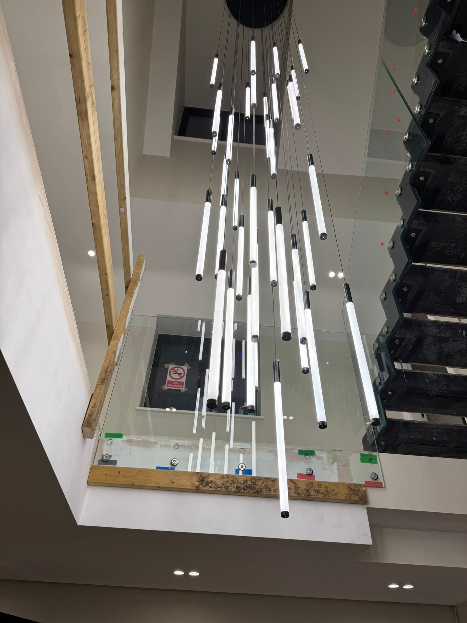 Avezzano pendant staircase chandelier by VORELLI cascading through a modern stairwell with vertical luxury lighting