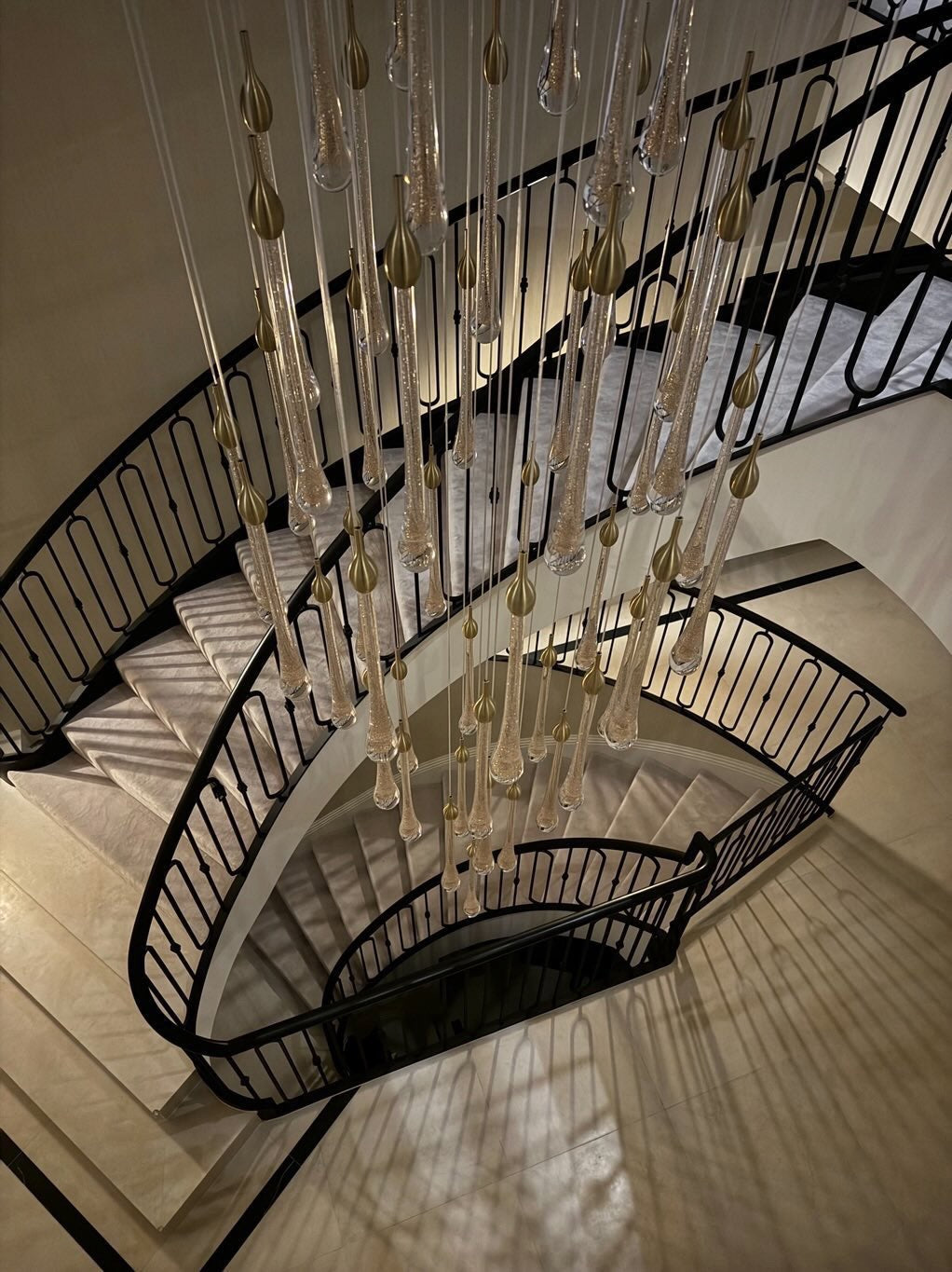 Curved staircase installation featuring VORELLI Foshan luxury pendant chandelier
