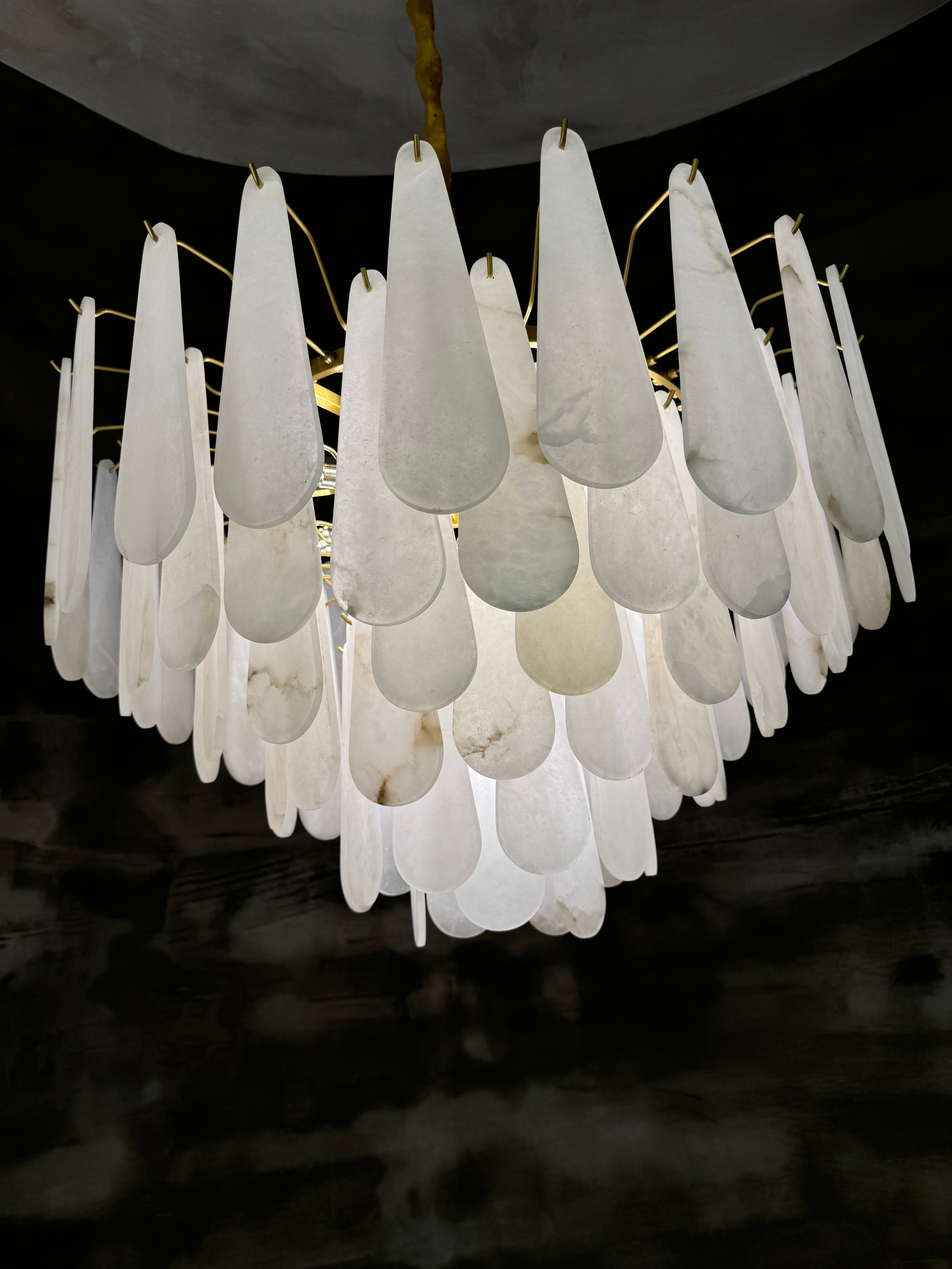 Glowing marble circular chandelier by VORELLI shown against a dark background highlighting its sculptural layered design